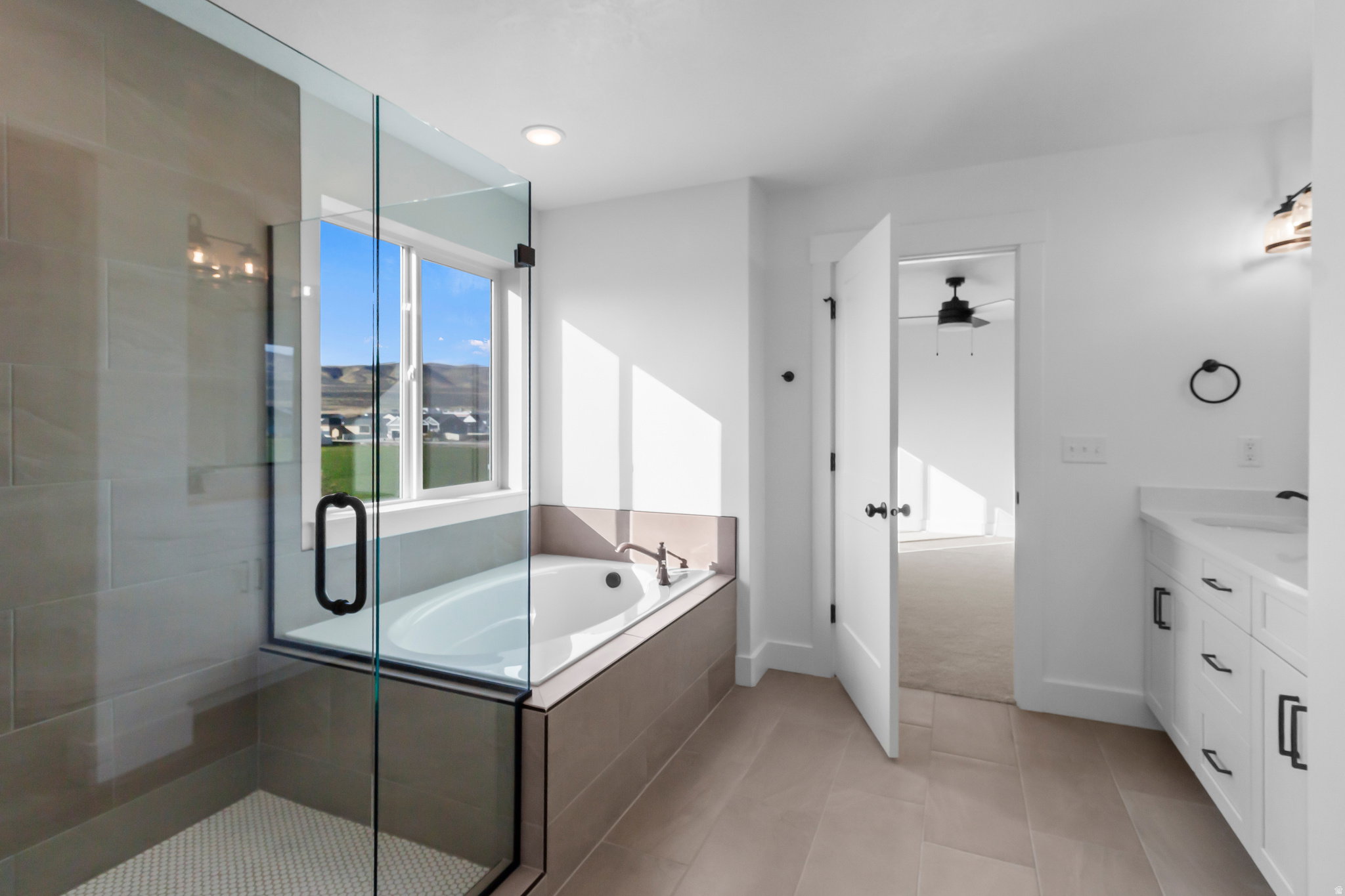 Glass-enclosed shower with tiled walls and a separate soaking tub