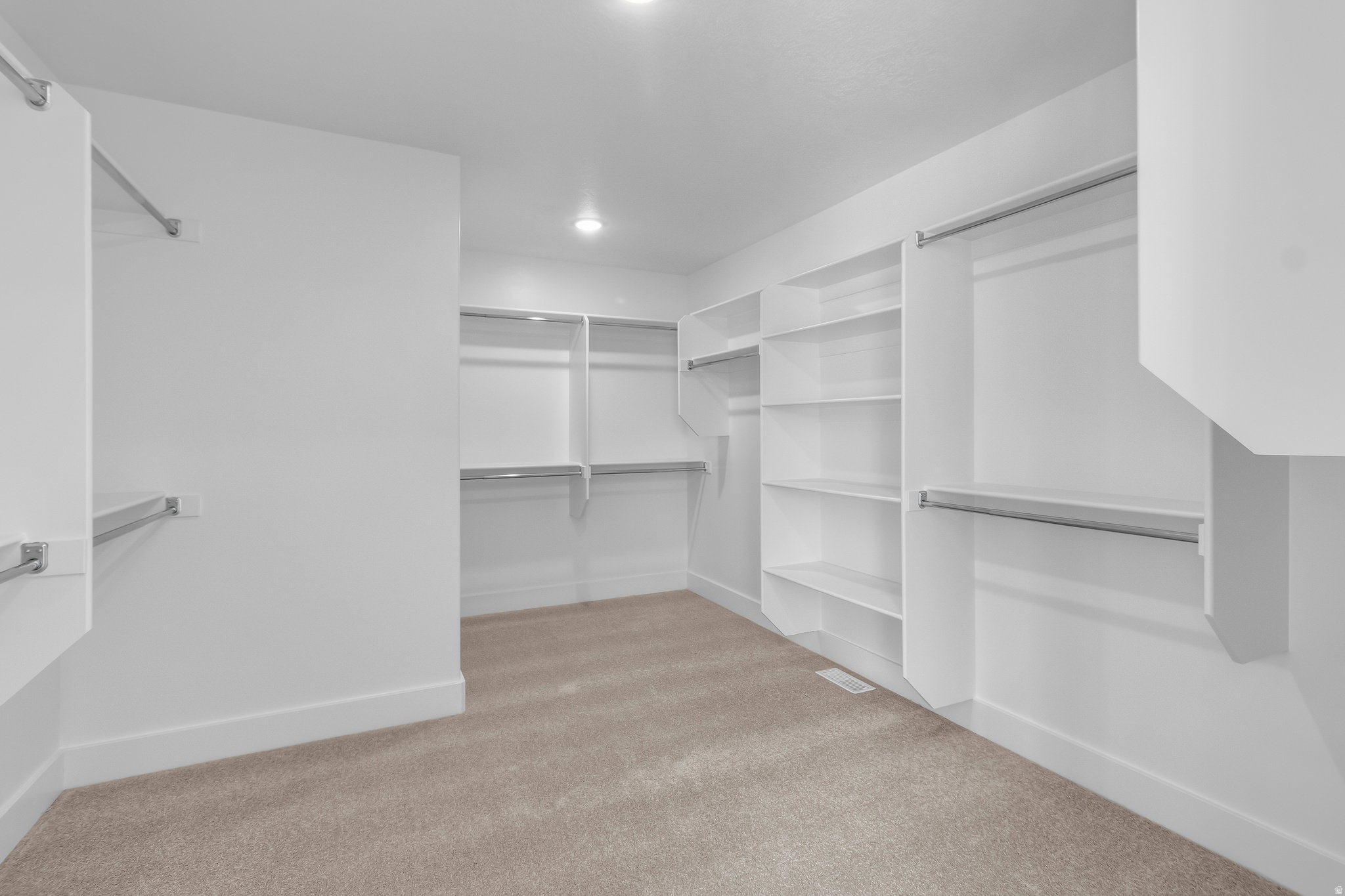 Spacious walk-in closet featuring built-in shelving, multiple hanging rods, and recessed lighting