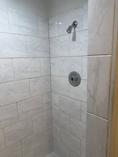White subway tile shower enclosure with a chrome showerhead and control