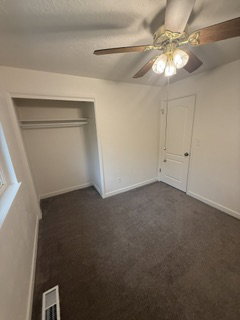 Room featuring neutral-toned carpeting, a ceiling fan with integrated lighting, and a white paneled door