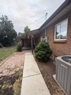 Brick exterior with a covered patio, concrete walkway, and established landscaping