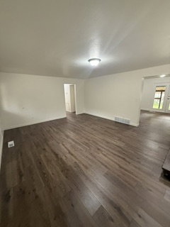 Spacious interior featuring wood-finish flooring, neutral wall tones, and overhead lighting