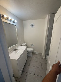 Bathroom featuring a white vanity with integrated sink, coordinating white toilet, and gray rectangular floor tiles