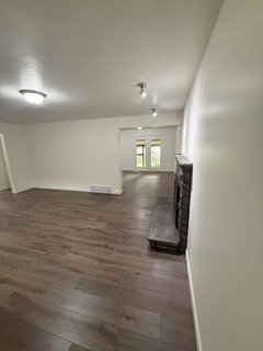 Spacious interior featuring wood-finish flooring, a stone-clad fireplace with a hearth, recessed lighting, and a neutral color palette