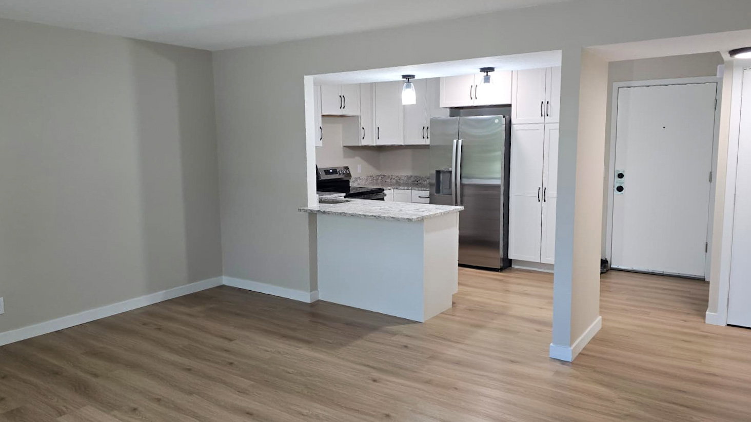 Open-concept living area featuring wood-finish flooring and neutral wall tones