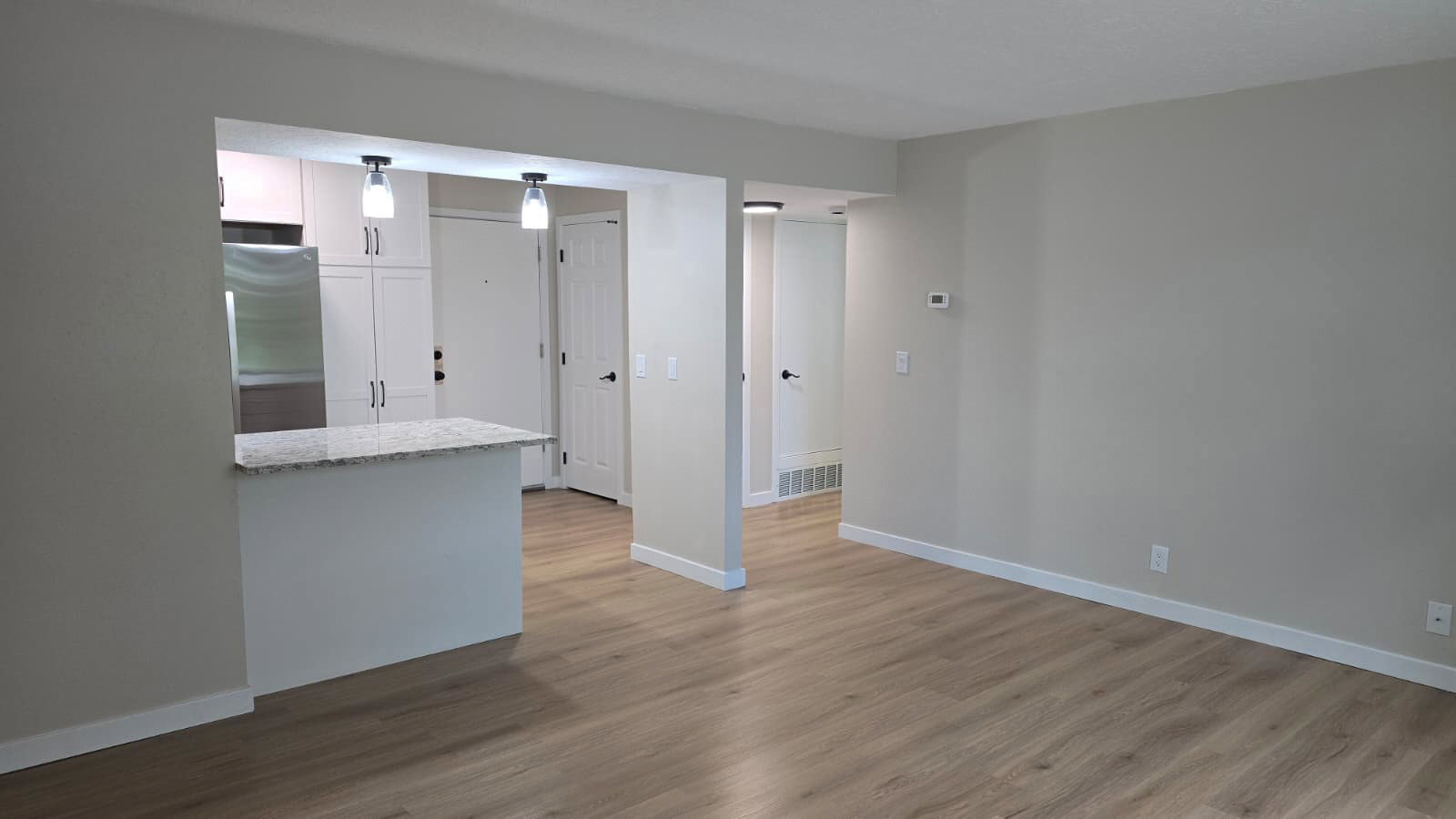 Open concept living area featuring wood-finish flooring and light-toned wall paint