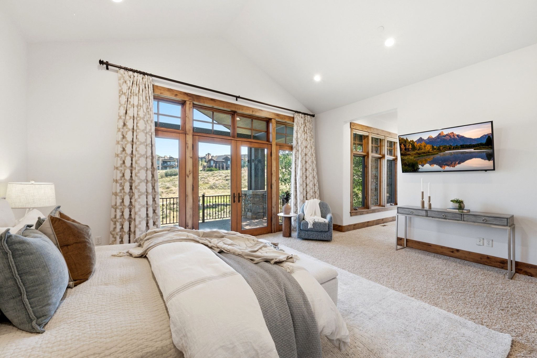 Vaulted ceiling bedroom featuring wood-framed double doors leading to an exterior balcony