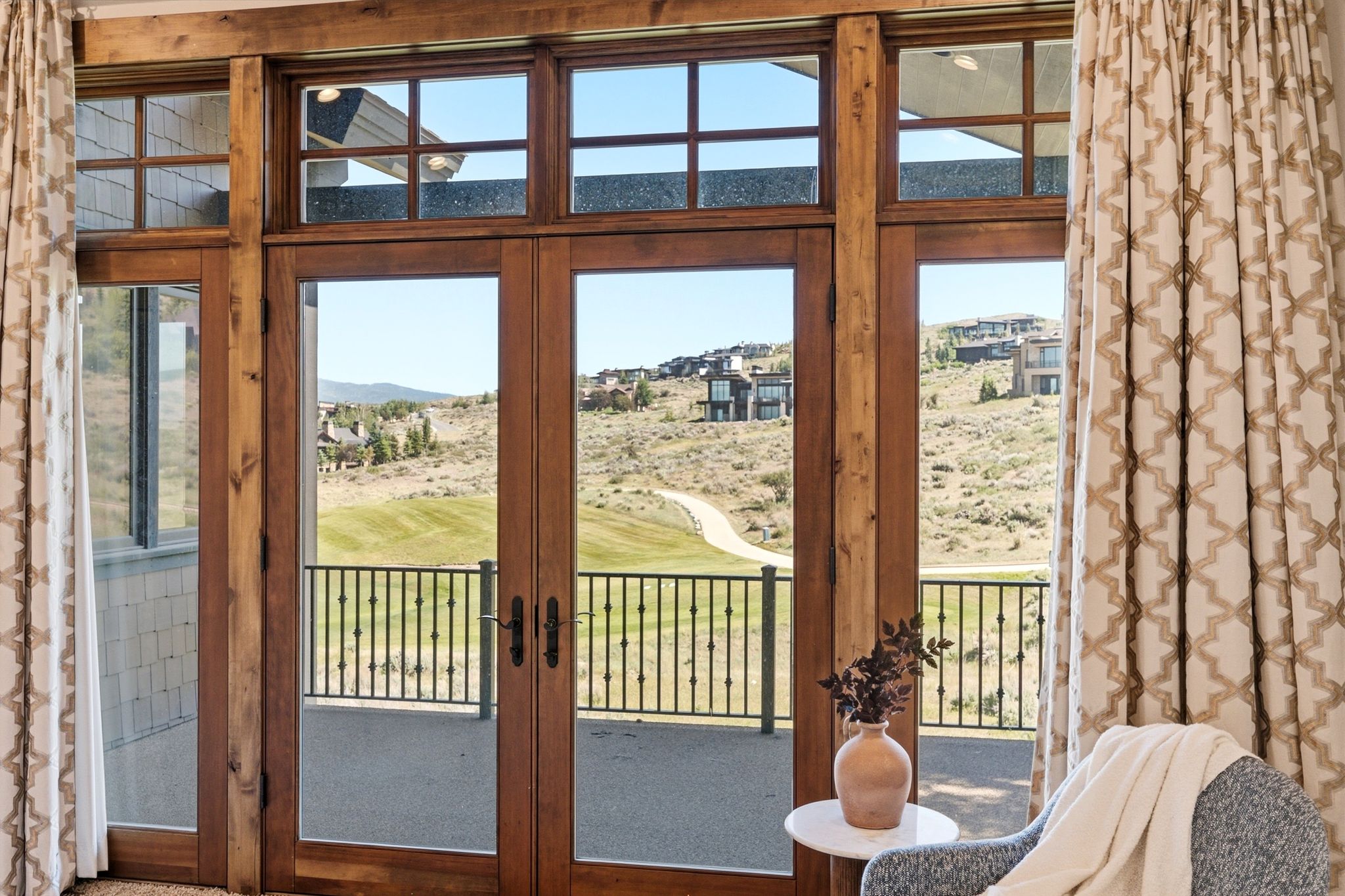 Wood-frame French doors with transom windows open to a private balcony