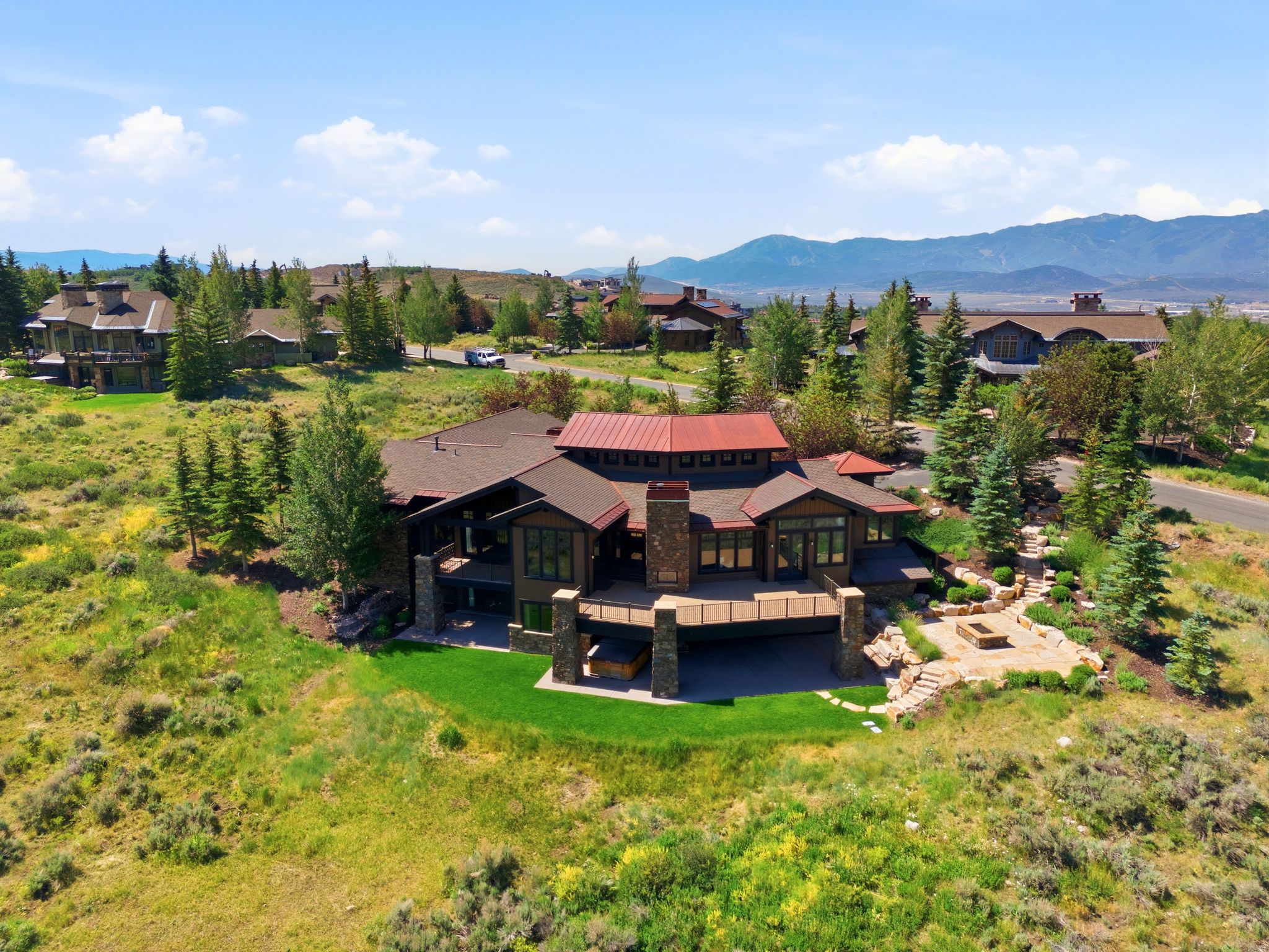 Expansive property featuring a multi-level wood and stone facade, a metal roof, and an upper-level deck