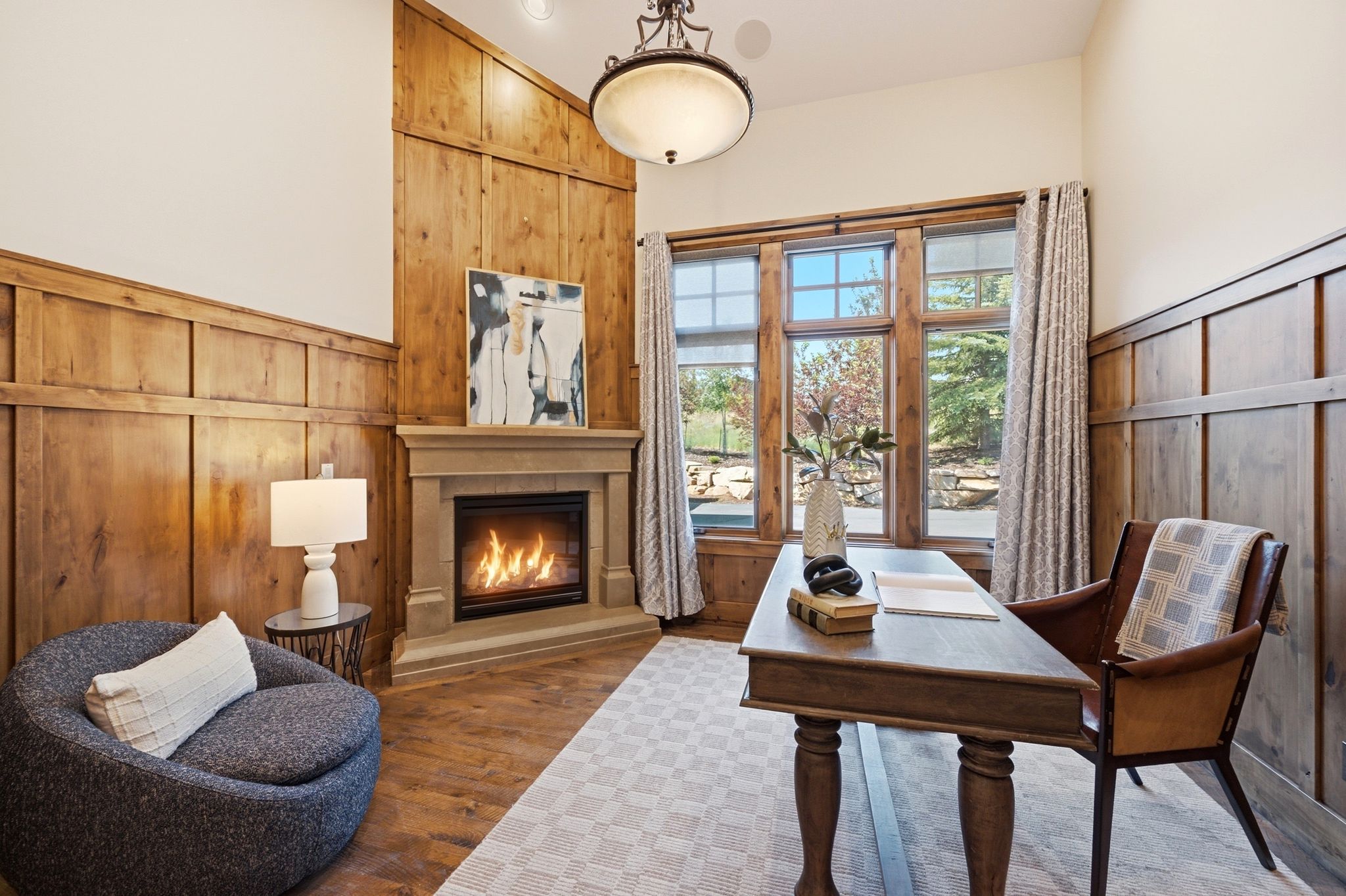 Room featuring wood-paneled walls, a corner fireplace with a stone surround, and wood-finish flooring