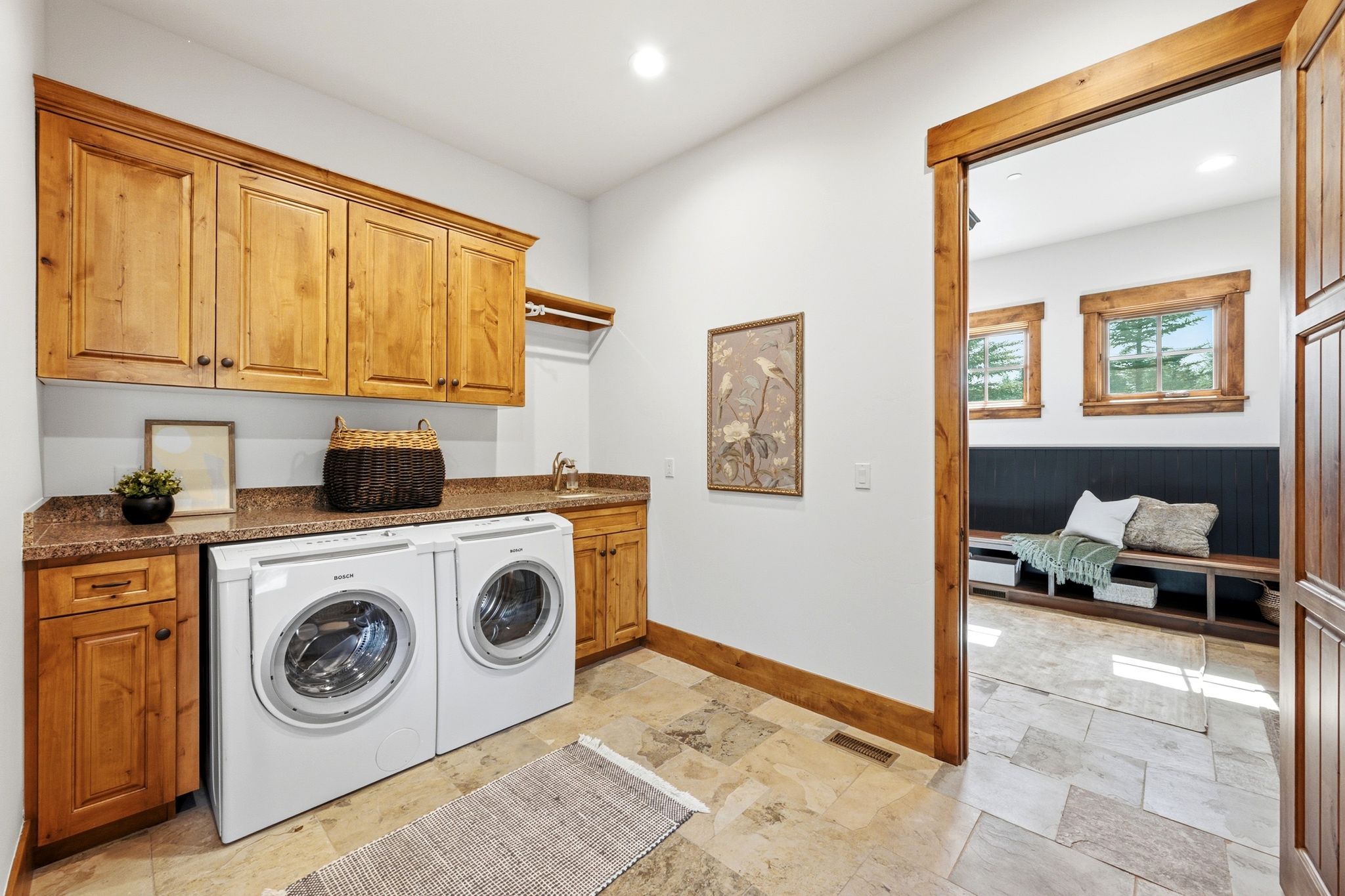 Laundry area featuring wood-finish cabinetry, a stone-finish countertop, and a utility sink