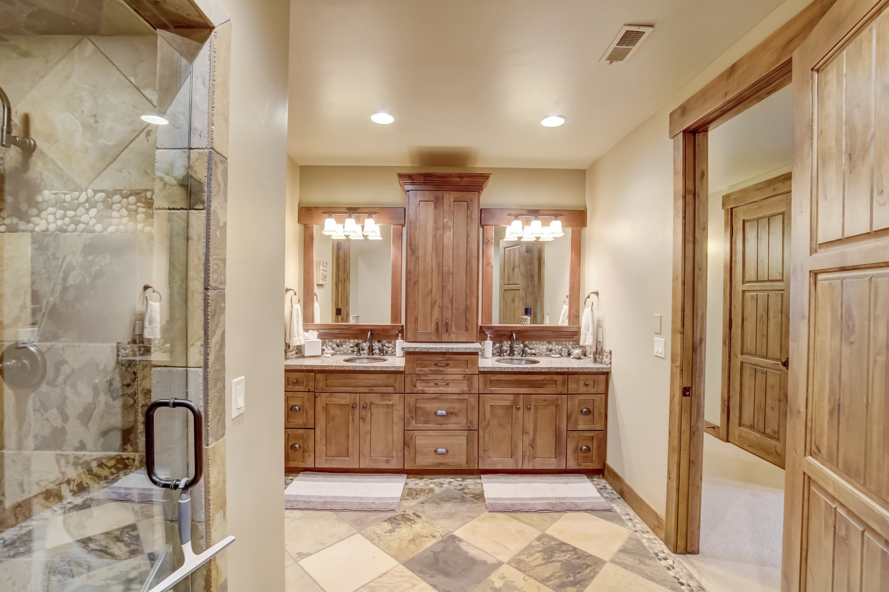 Bathroom featuring a dual vanity with wood cabinetry, granite countertops, and individual framed mirrors