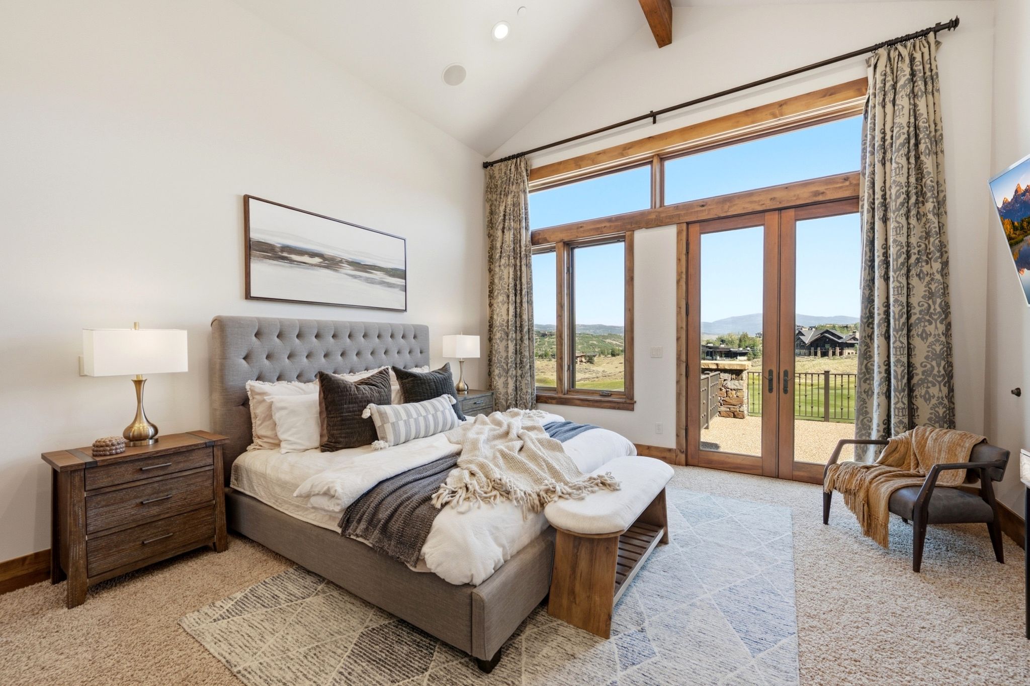 Vaulted ceiling bedroom with a full-height wall of windows and French doors