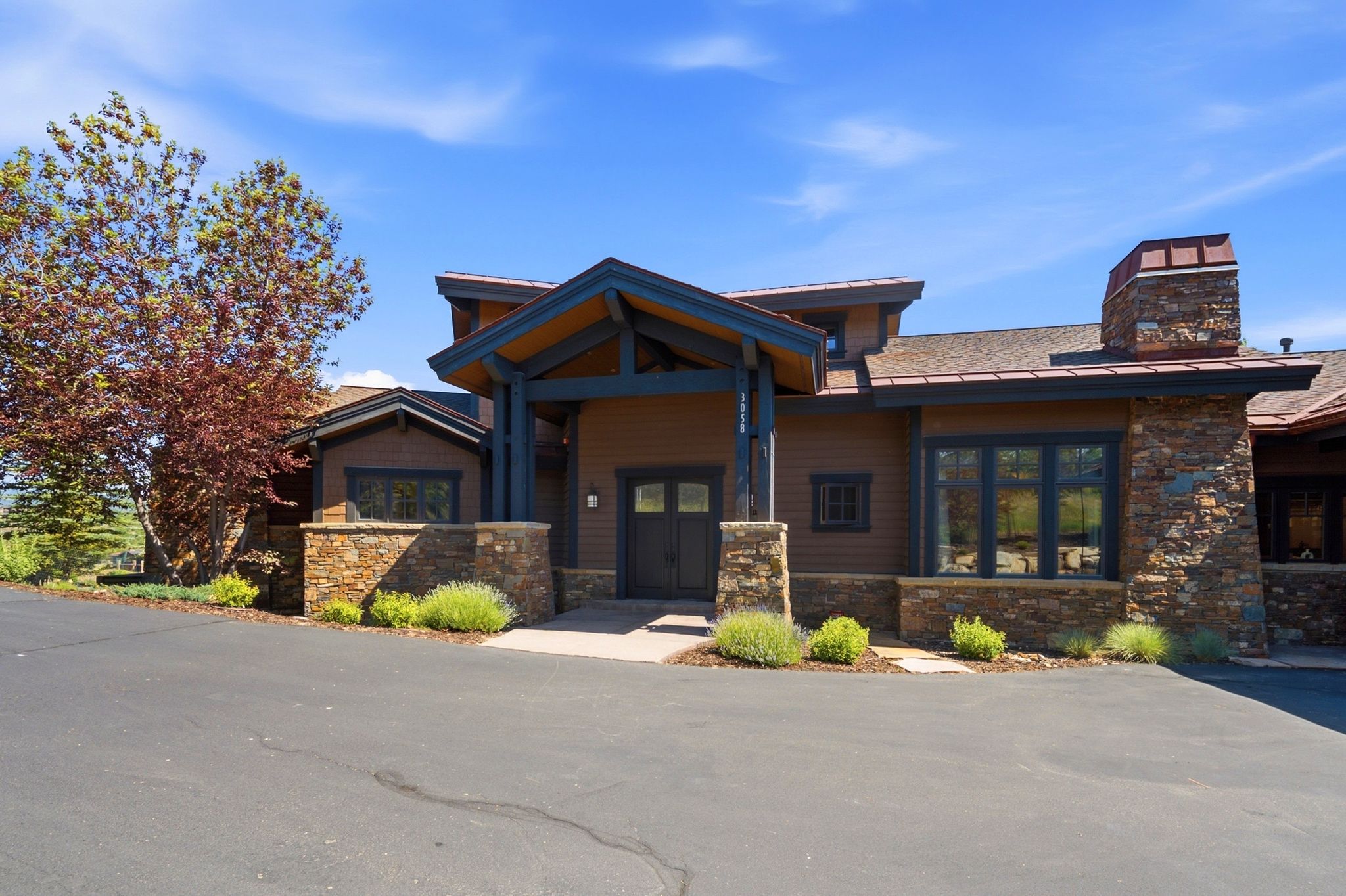 Stone and wood-sided exterior featuring a prominent covered entry with exposed beams