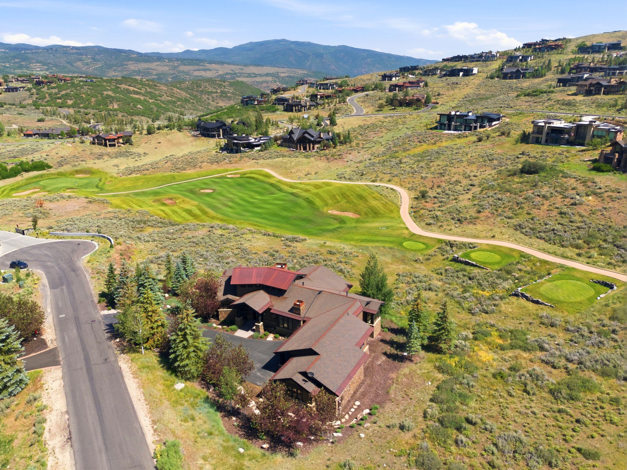 Hillside residence featuring a multi-level roofline, stone and wood exterior finishes, and mature landscaping