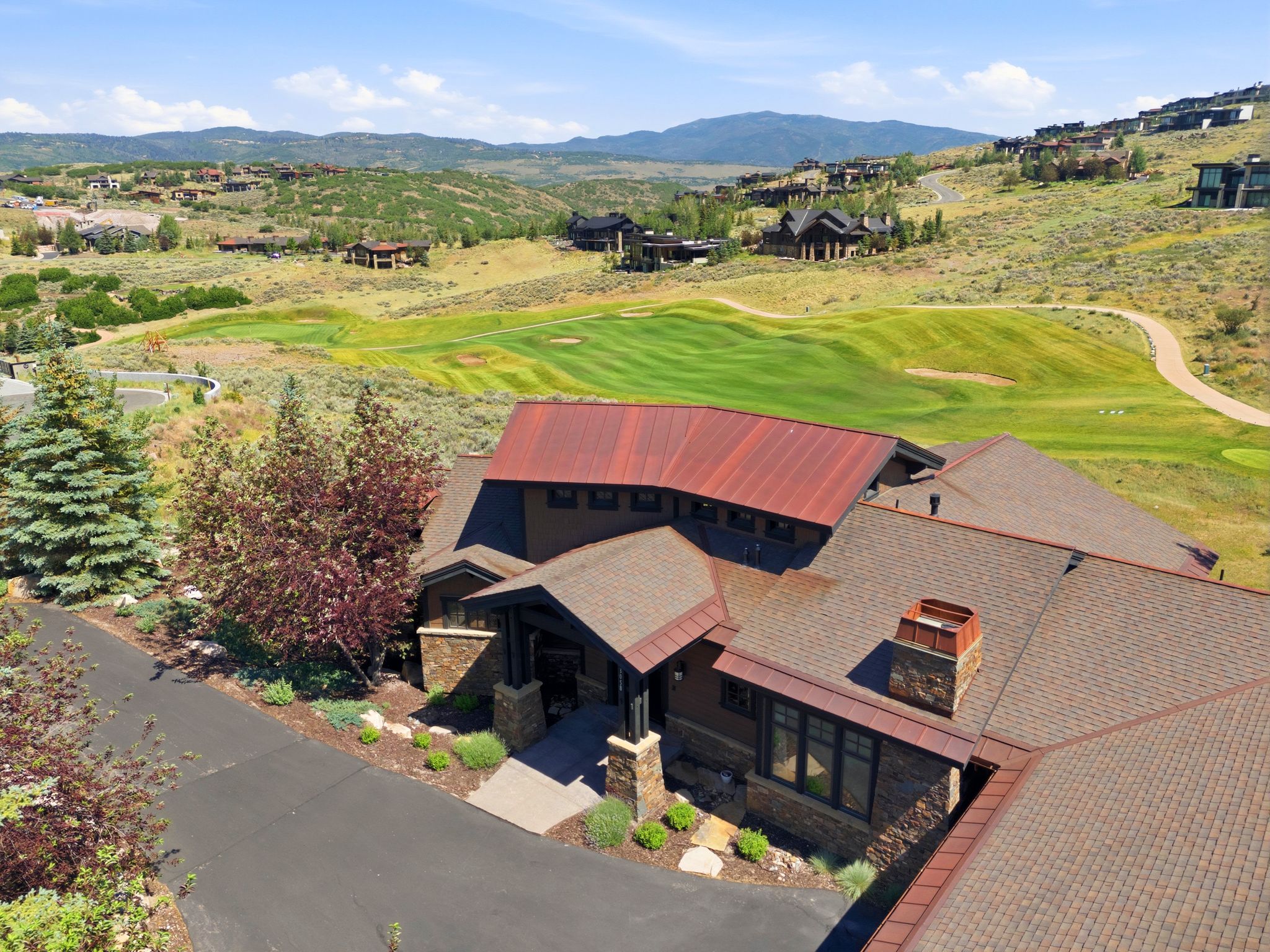 Architectural residence featuring a mix of brown asphalt shingles and a distinct red metal roof