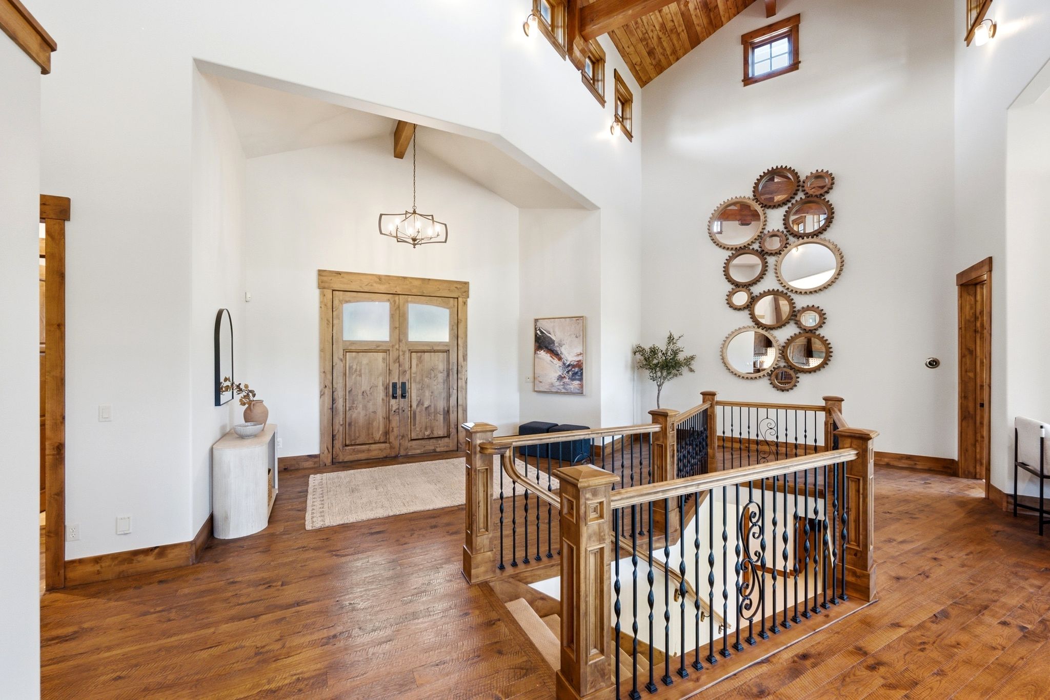 Grand foyer featuring vaulted ceilings with exposed wood beams, wood-finish flooring, a wrought iron and wood staircase, and double entry doors with frosted glass panels