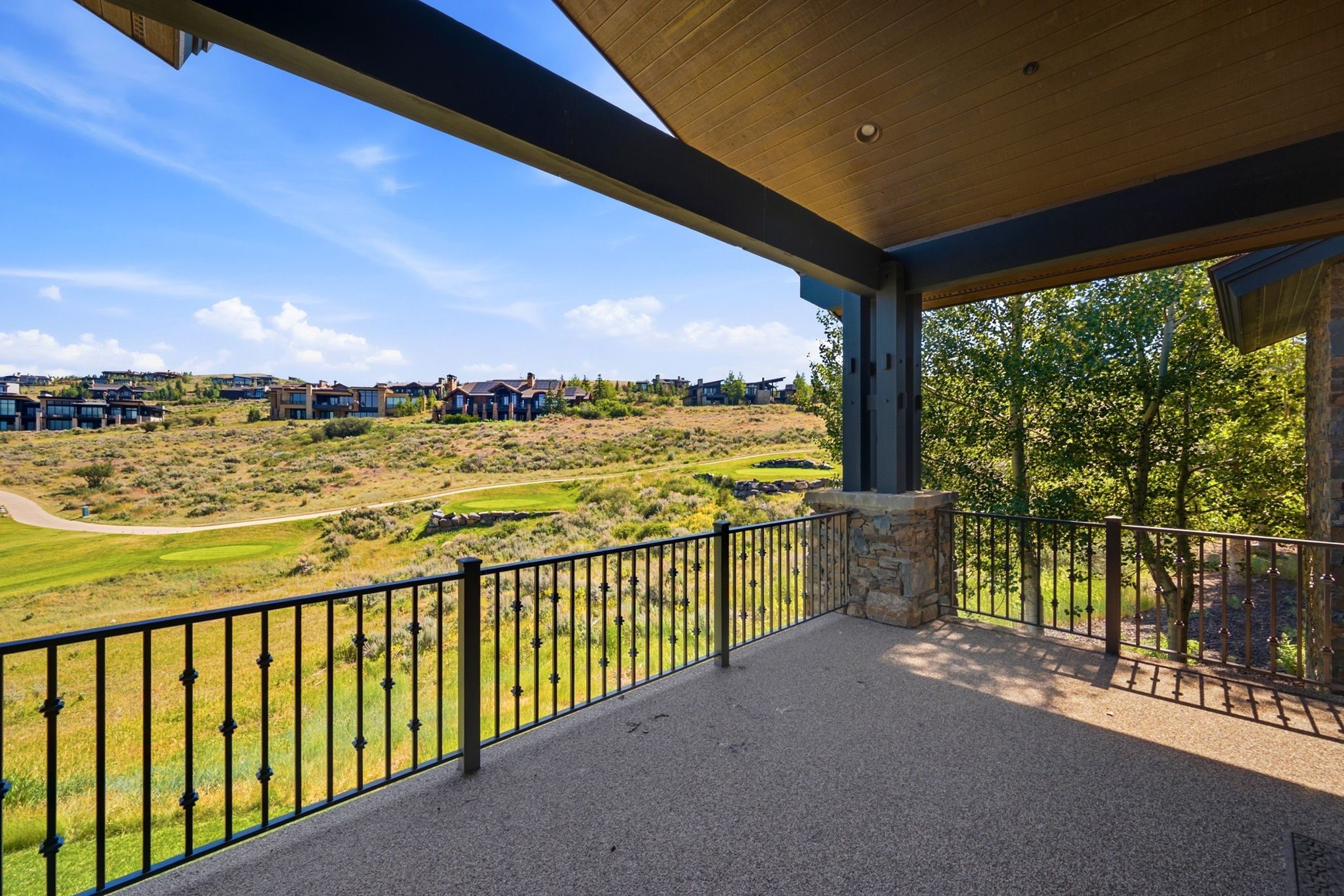 Expansive covered patio featuring a textured concrete surface and ornate black metal railings