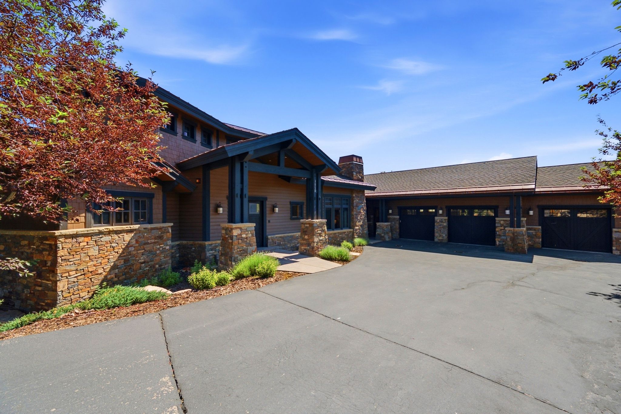 Exterior featuring a stacked stone foundation, wood siding, and dark trim