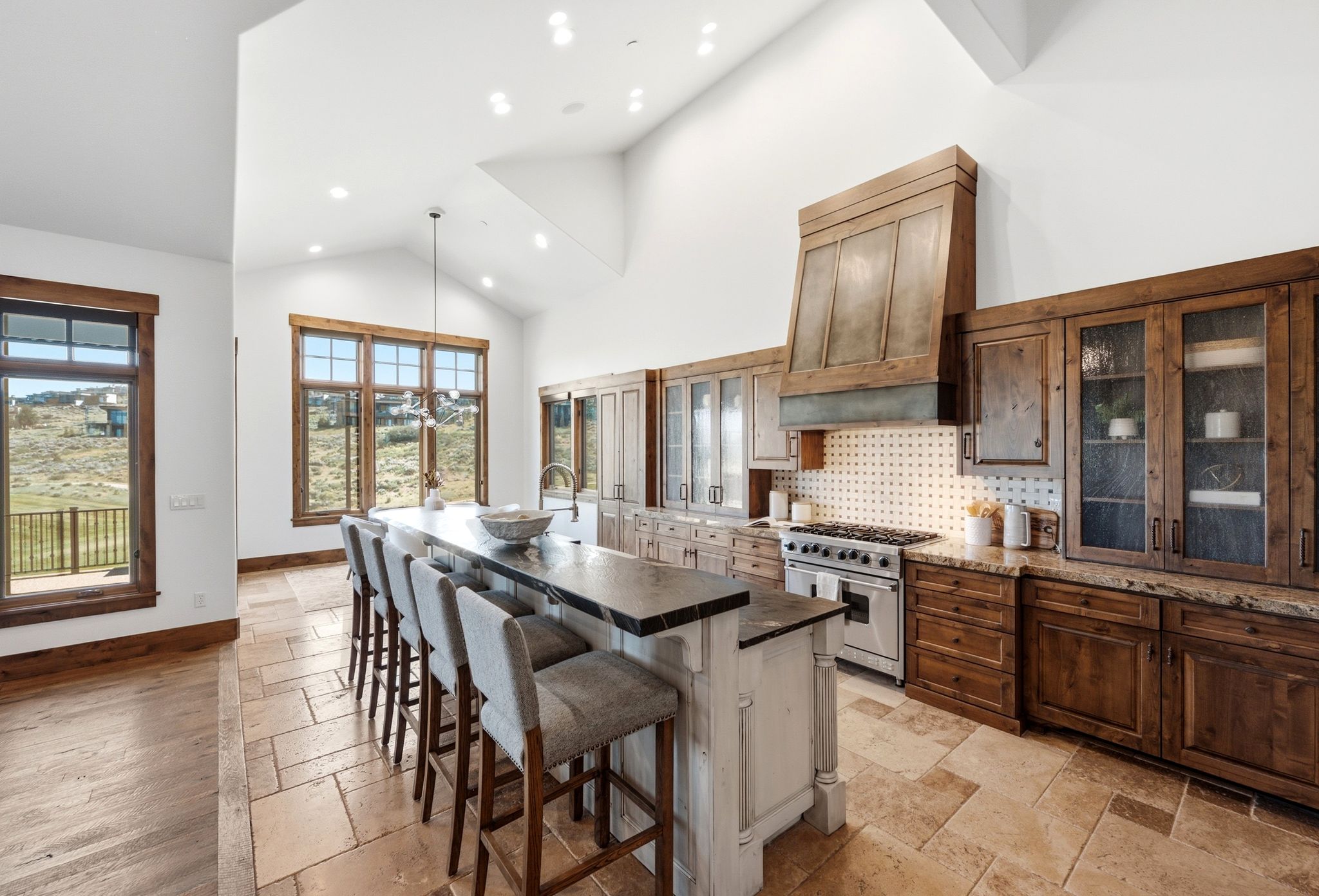 Open-concept kitchen featuring a large island with seating, a professional-grade range, custom wood cabinetry, and vaulted ceilings