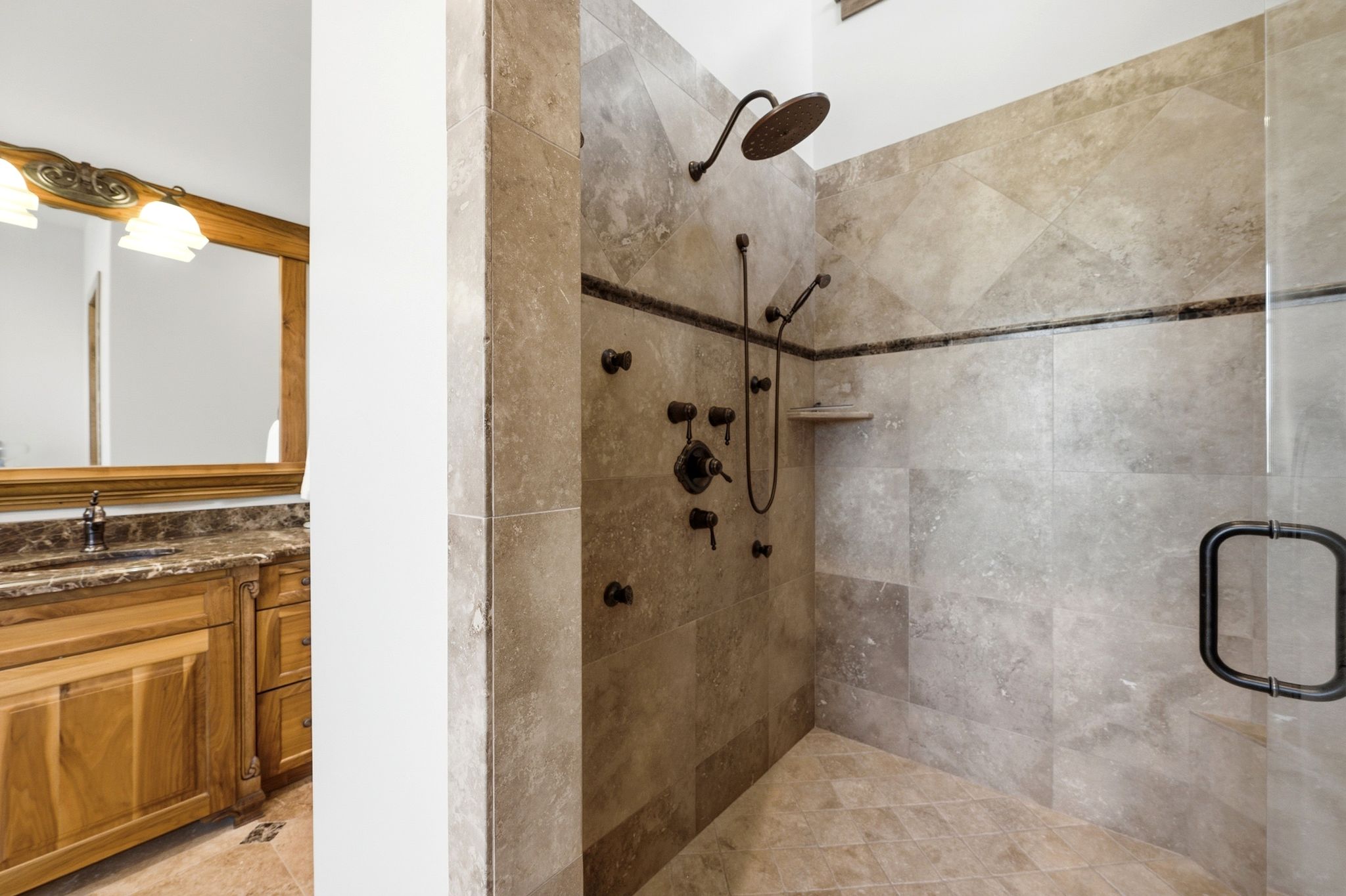 Spacious walk-in shower with stone tile walls, floor, and decorative accent band