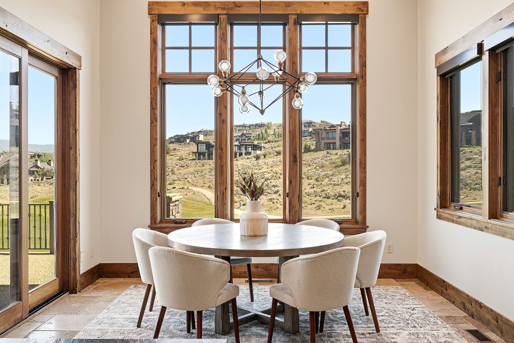 Dining space featuring a large picture window with rustic wood trim and a modern chandelier