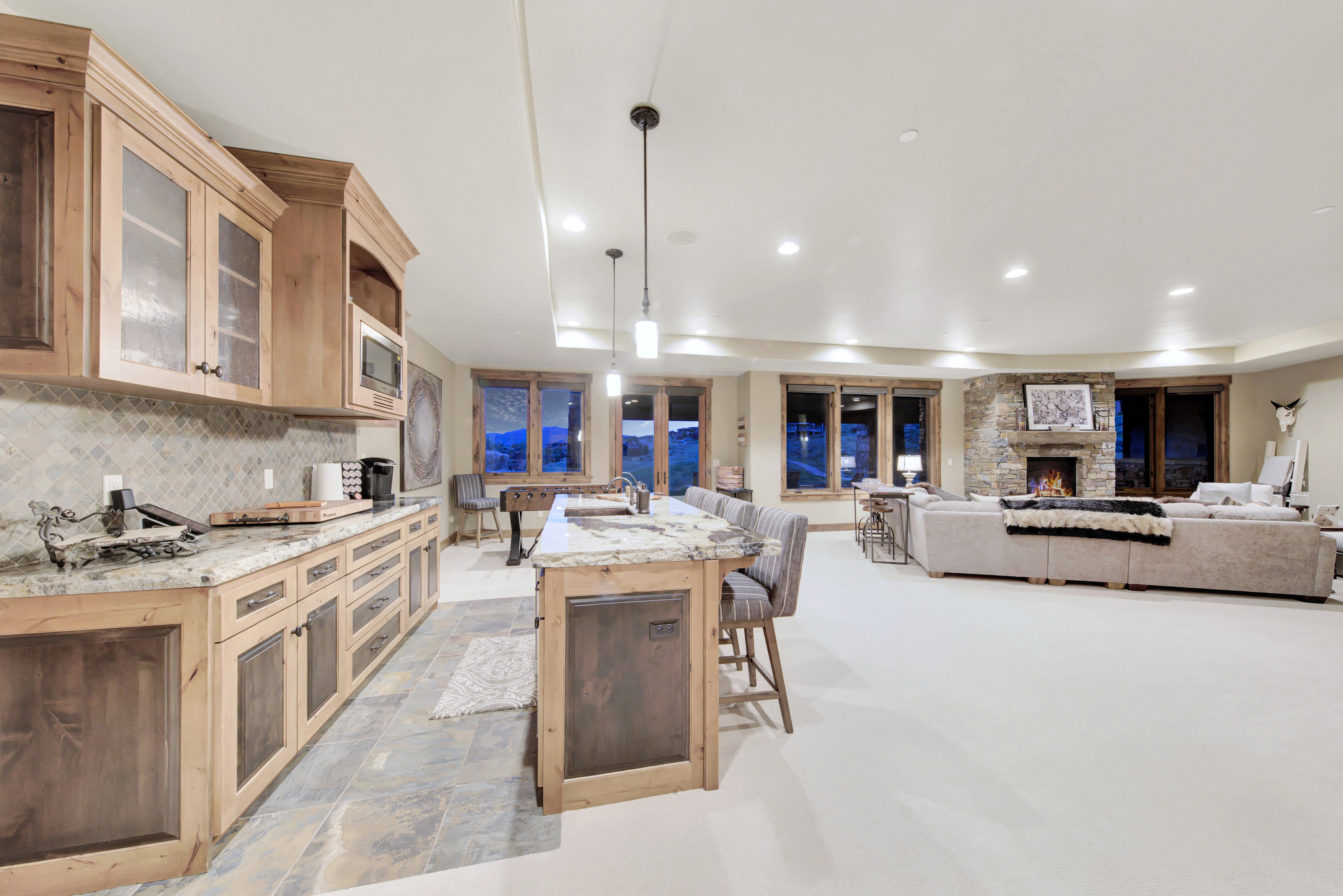 Open-concept living space featuring a stone-clad fireplace and multiple windows
