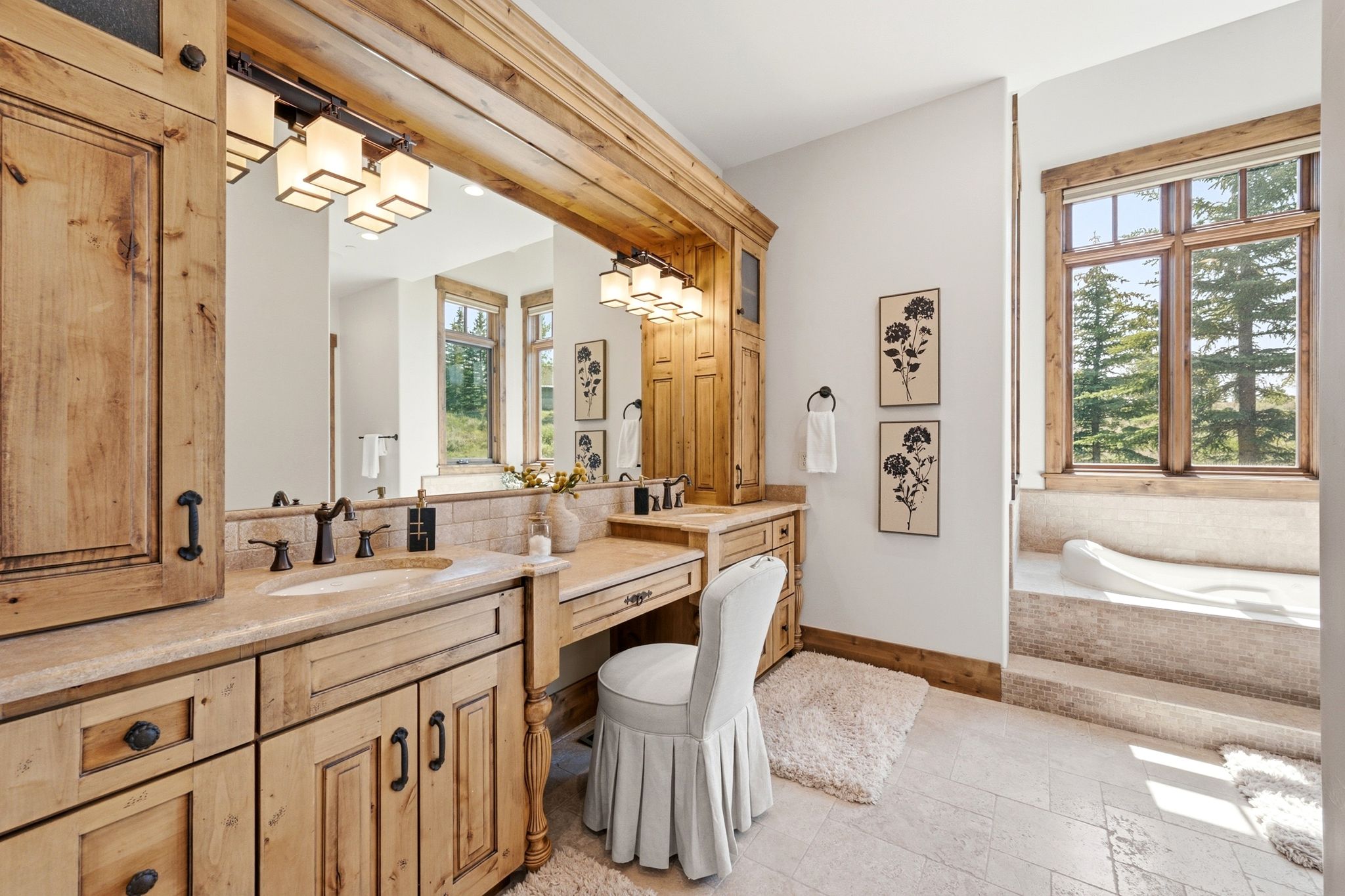 Spacious bathroom featuring natural wood cabinetry, a built-in vanity with a stone countertop, a large framed mirror, and an integrated soaking tub with tiled surround