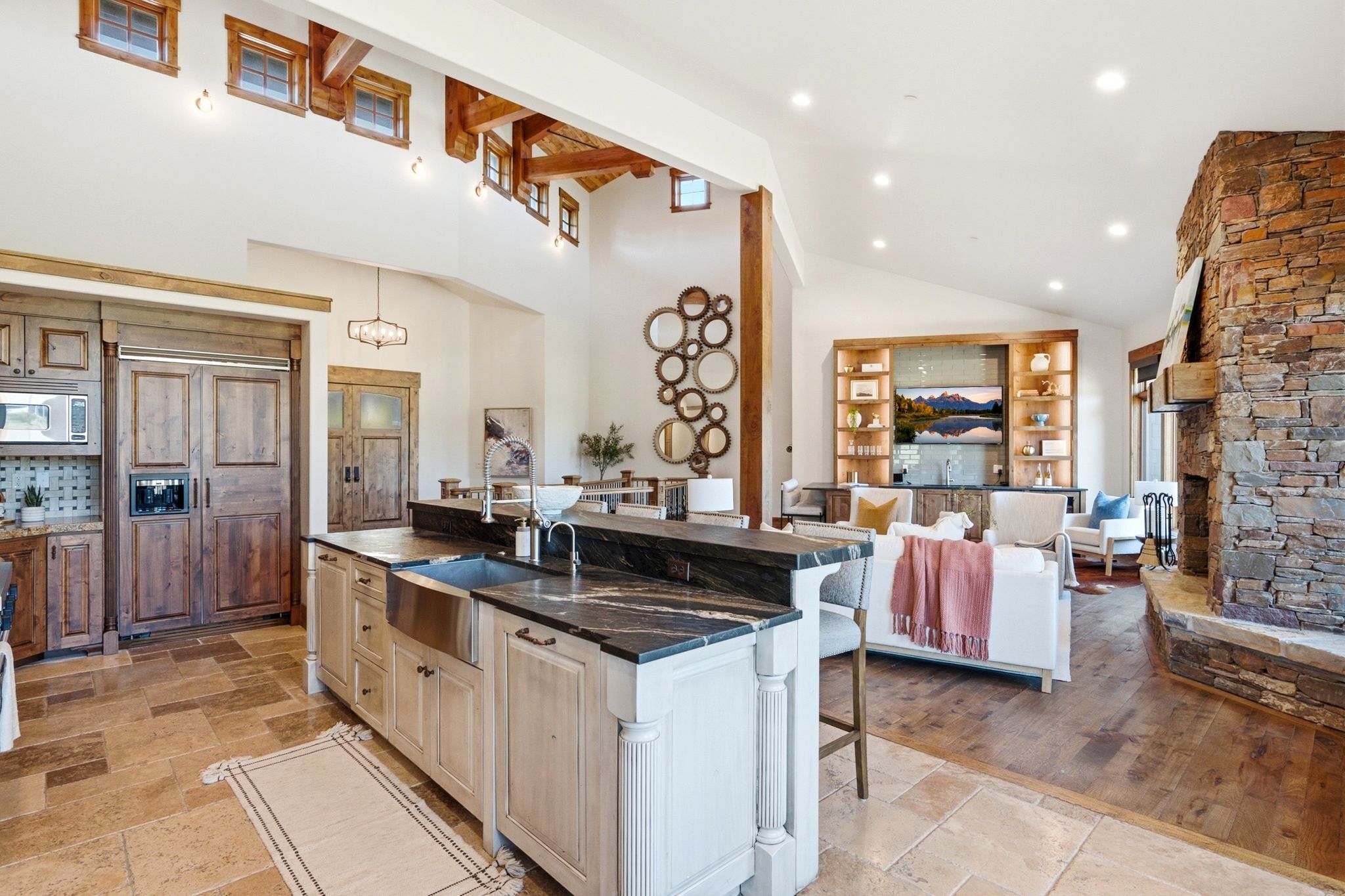 Gourmet kitchen with an integrated refrigerator, stainless steel farmhouse sink, and stone countertops