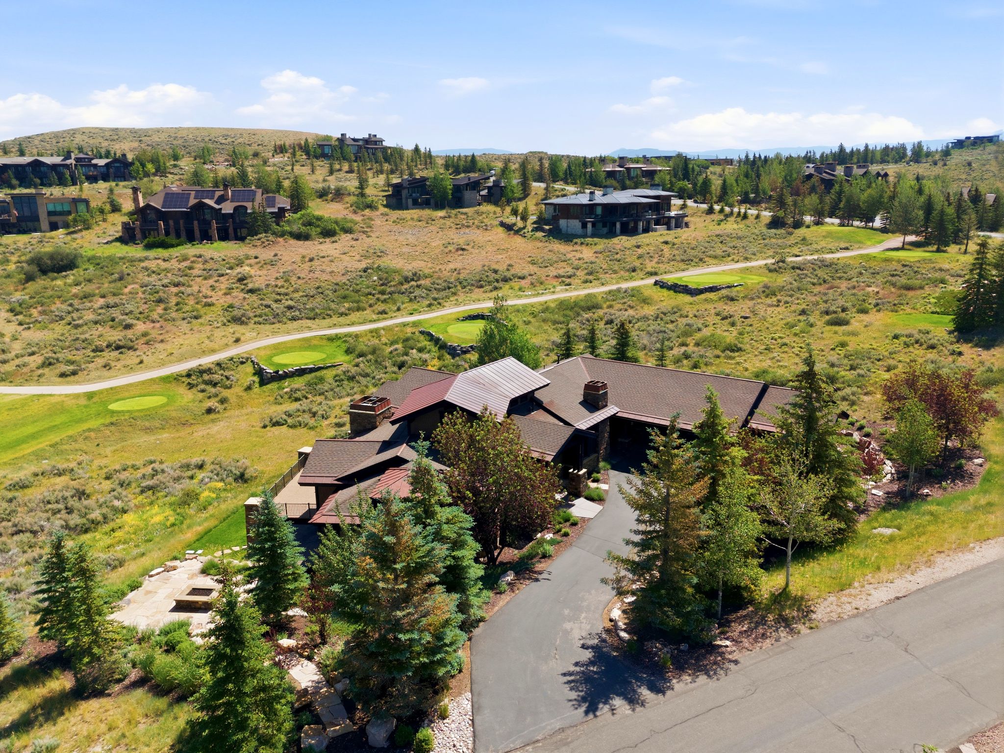 Expansive property featuring a multi-level roofline, stone chimney, and a paved driveway