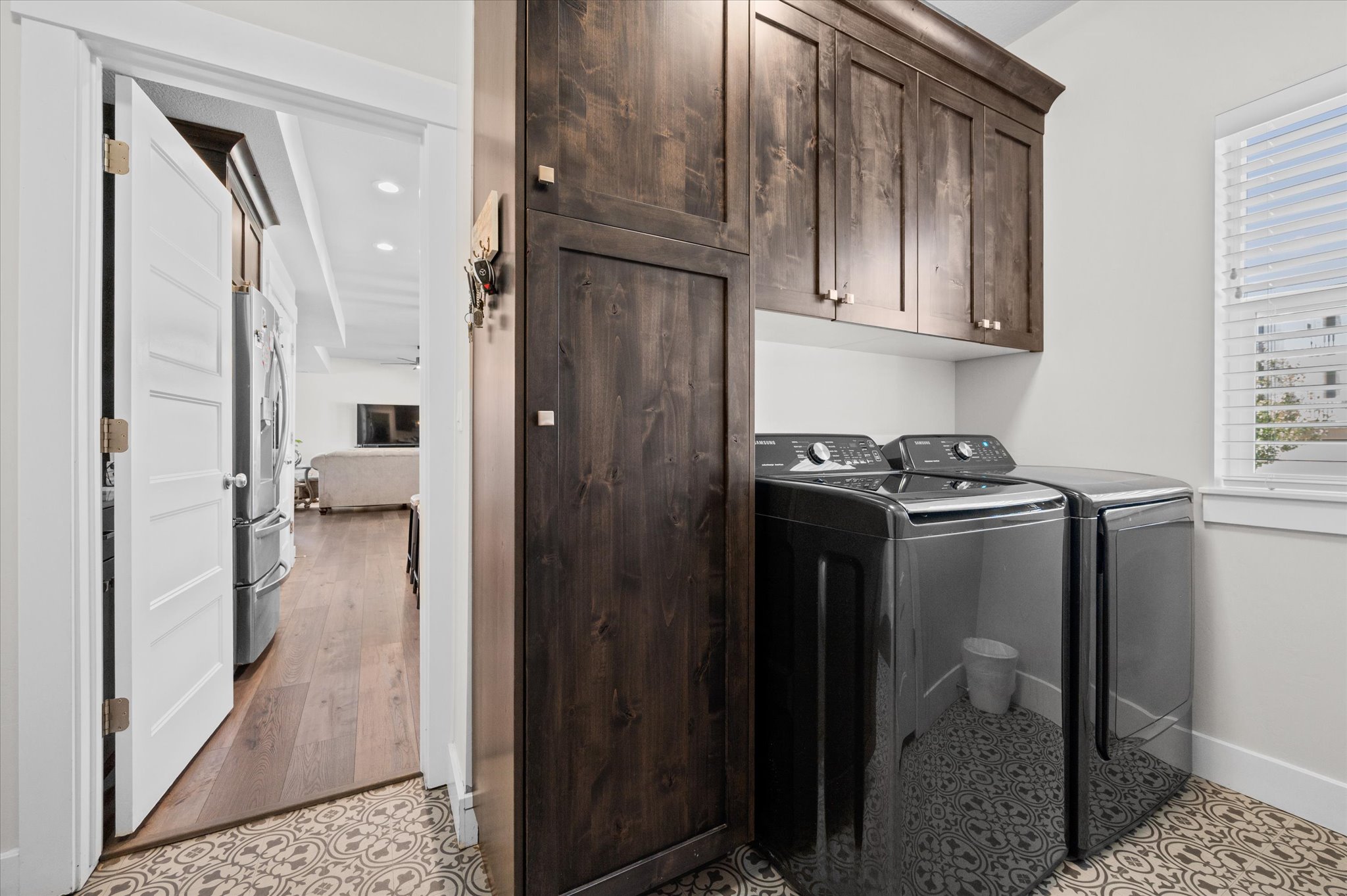 Dedicated laundry area featuring dark wood-finish cabinetry, a tall pantry cabinet, and patterned floor
