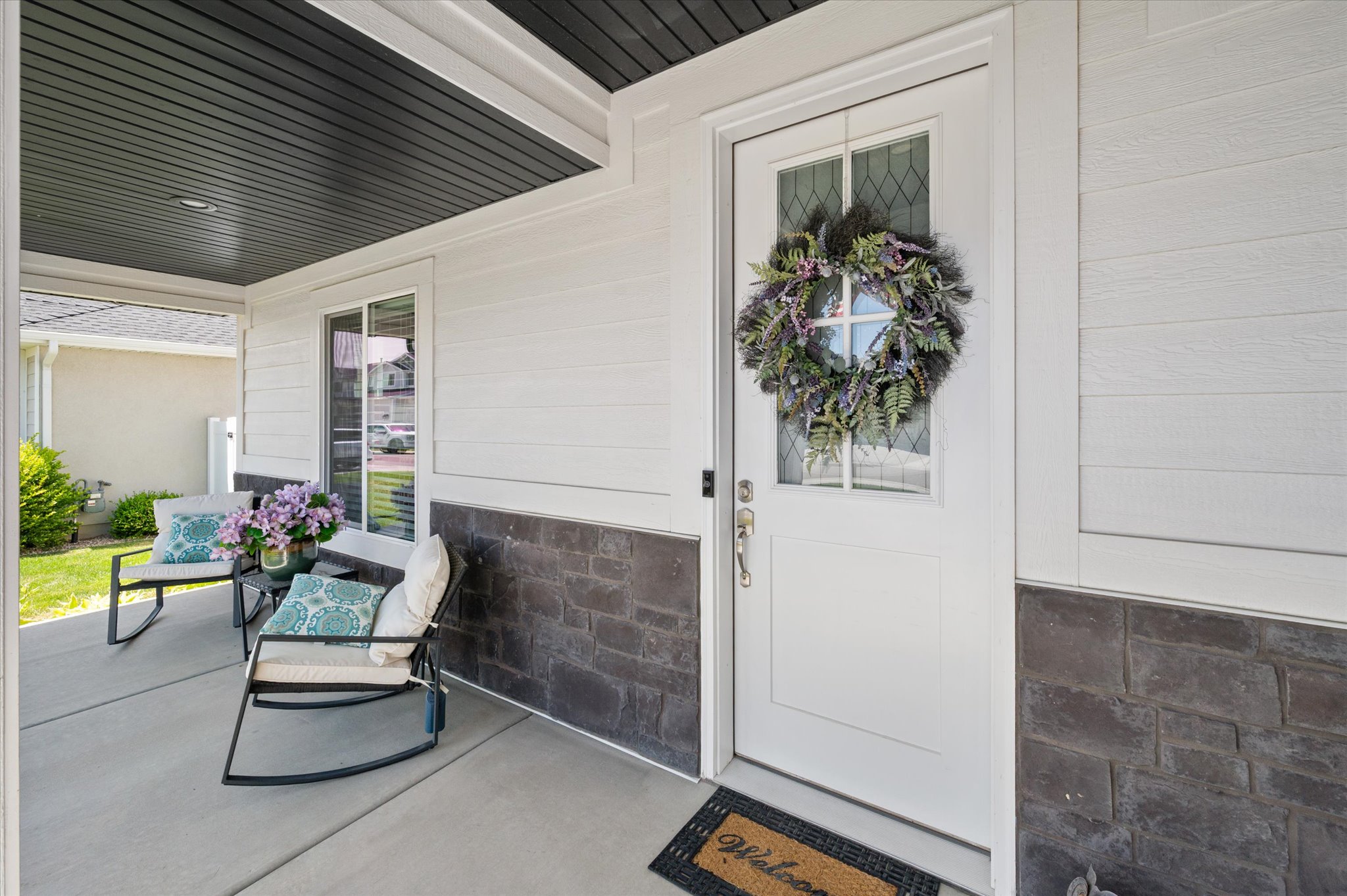 Covered front porch featuring  a white entry door with glass panels