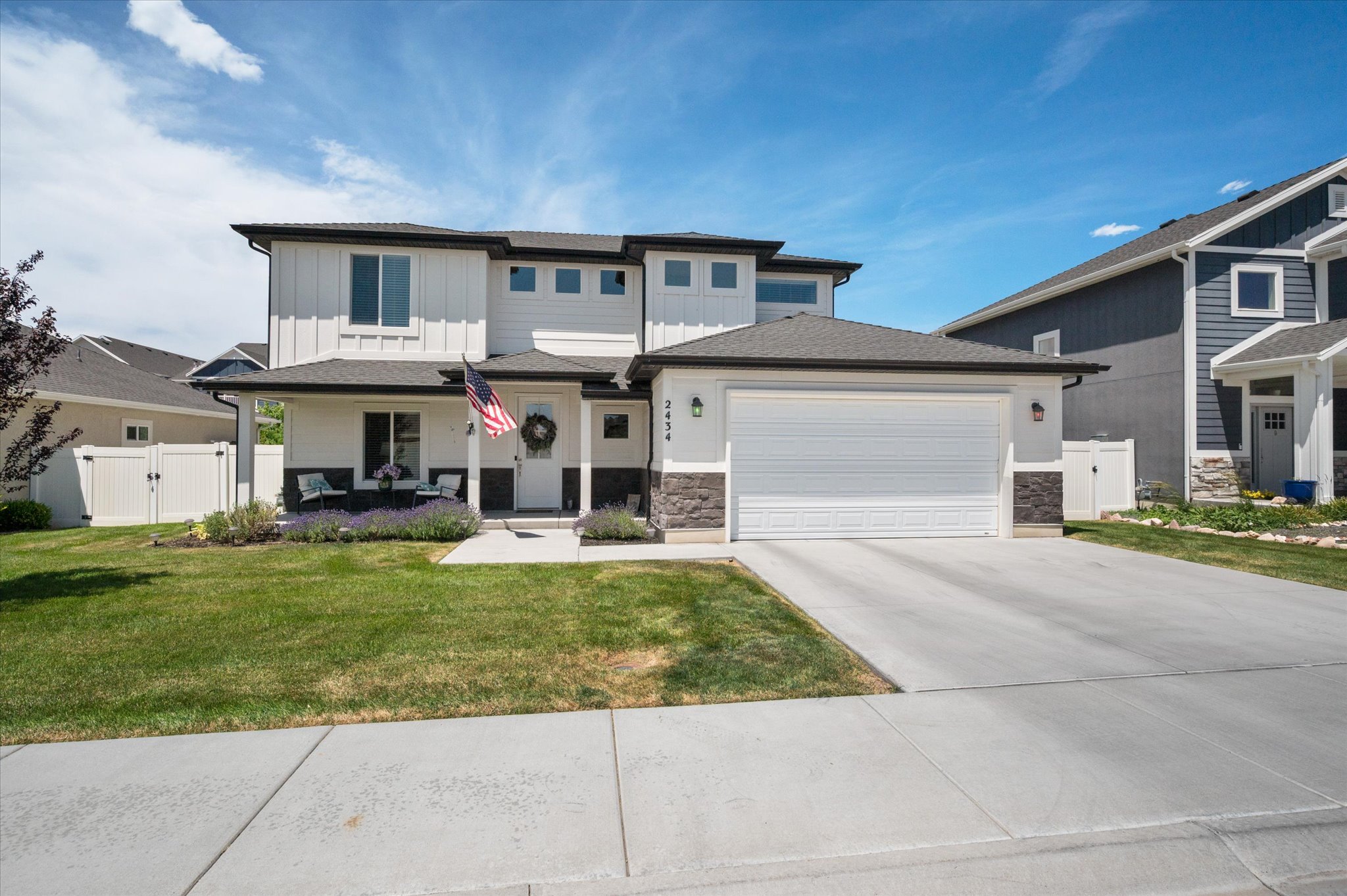 Modern two-story residence featuring a board and batten facade, a covered front porch, and an attached two-car garage