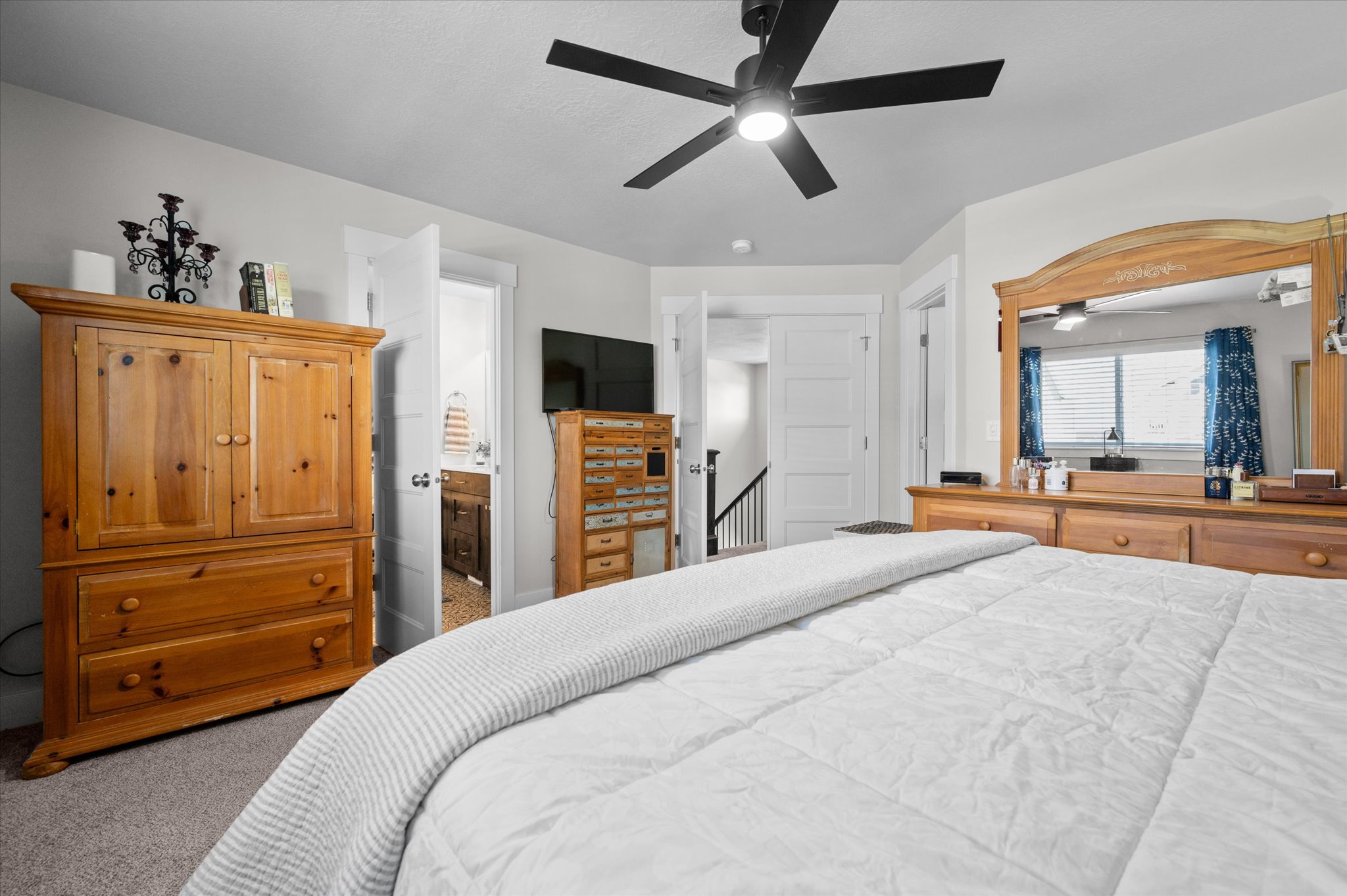 Carpeted room with a ceiling fan light fixture, white interior doors, and neutral wall paint