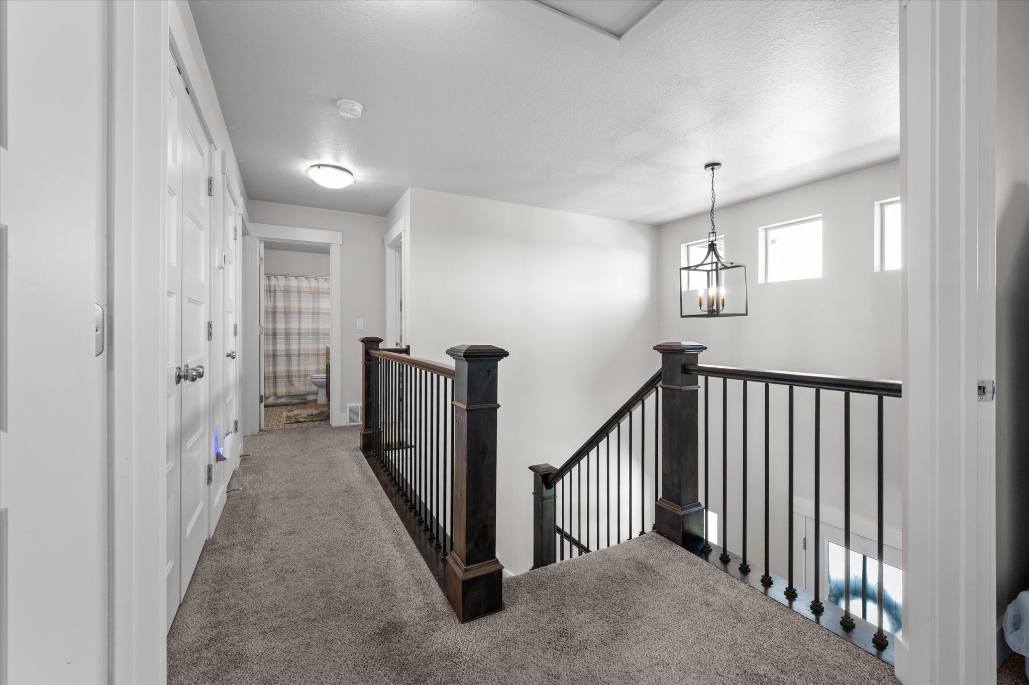 Upper-level hallway with carpet flooring and light gray walls