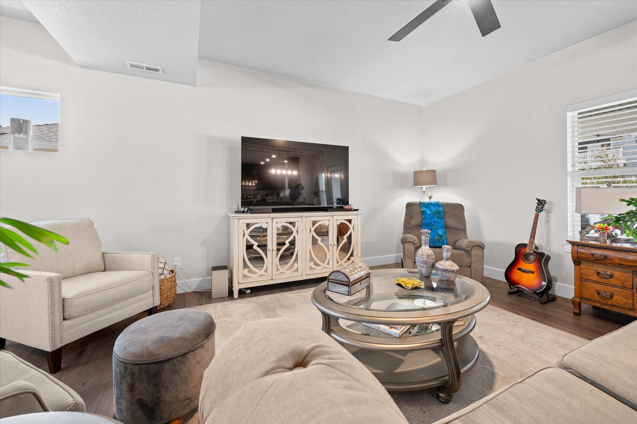 Bright living area featuring wood-finish flooring, a ceiling fan, and white walls