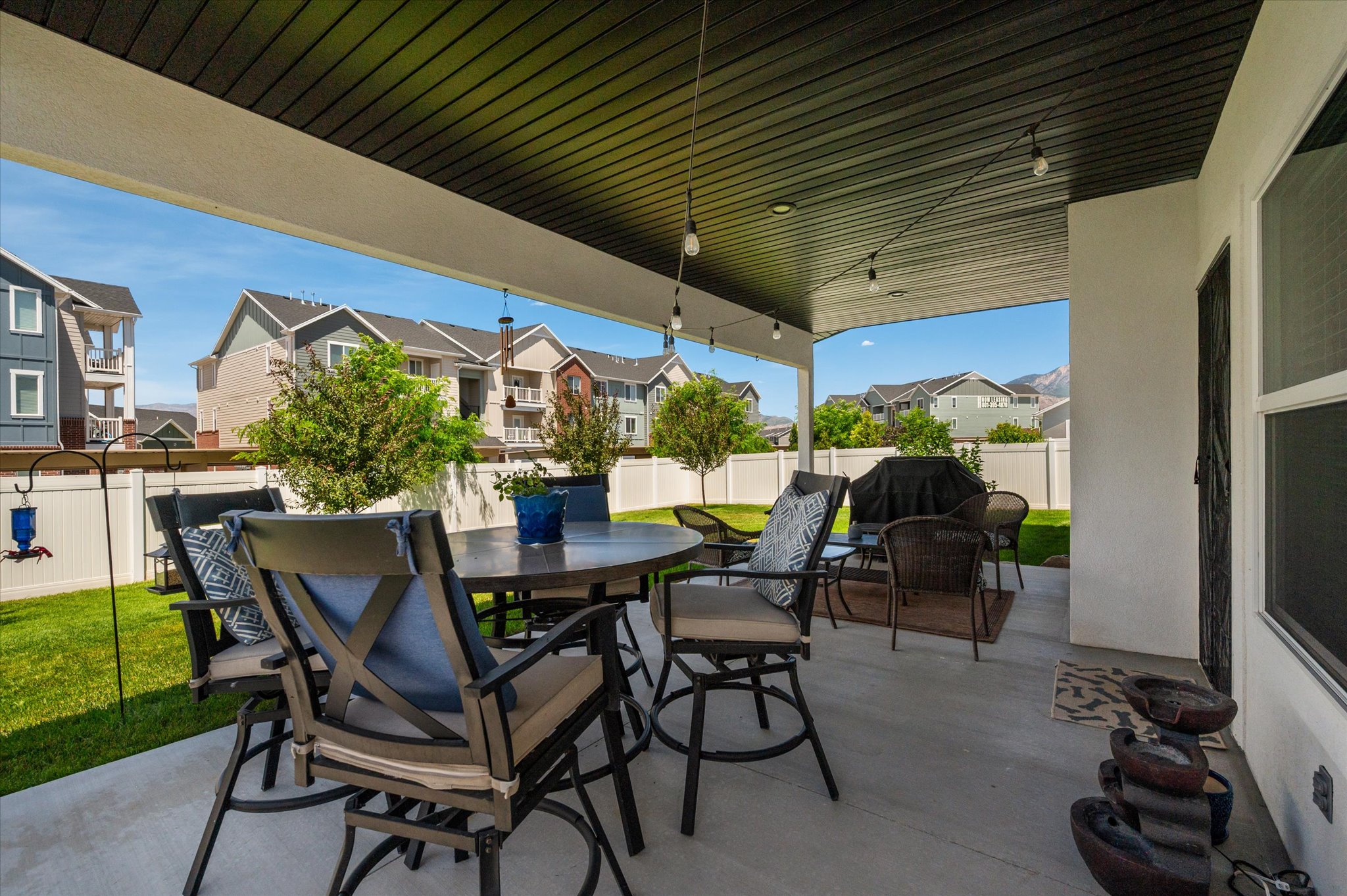 Covered patio featuring string lighting, concrete flooring, and a dark ceiling
