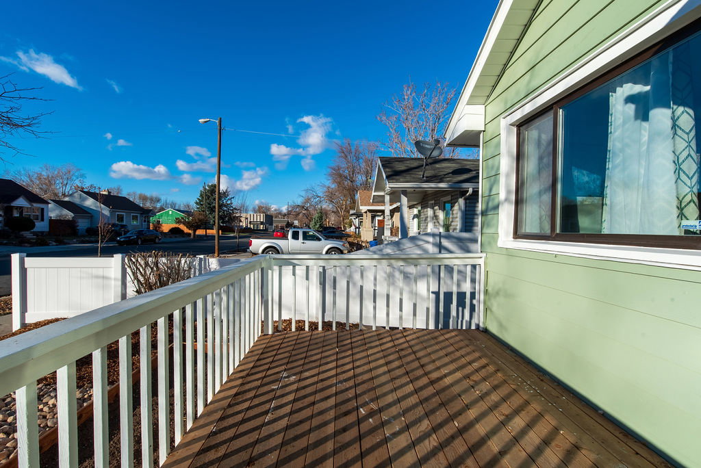 Wood-finish porch decking with white railing and a light green exterior wall