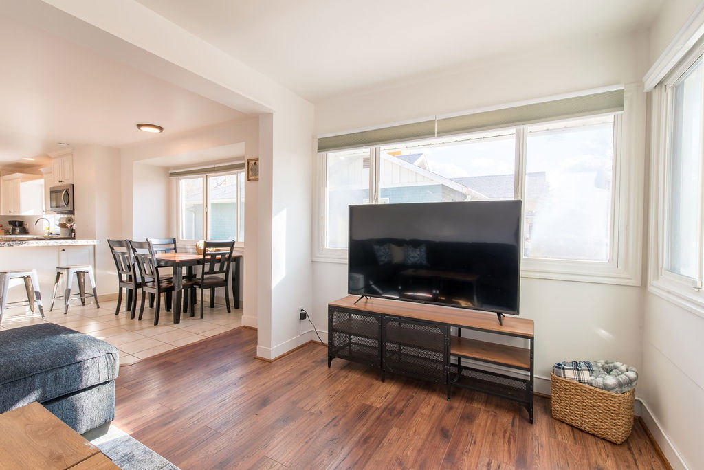 Open-concept living area featuring wood-finish flooring and ample natural light from multiple windows