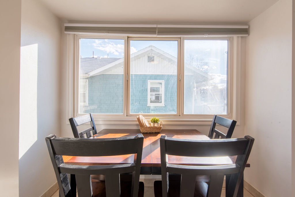 Bright room featuring a large window with three panes, white trim, and a roller shade