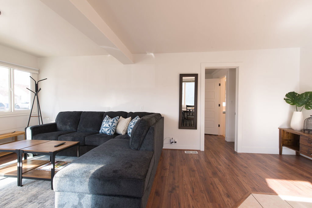 Spacious living area featuring wood-finish flooring, white walls, and a large window providing natural light