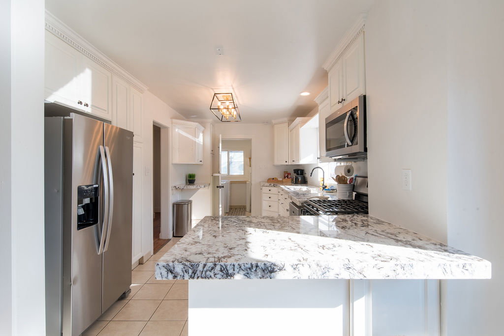 Kitchen featuring white cabinetry, stainless steel appliances, a gas range, and a breakfast bar with a patterned countertop