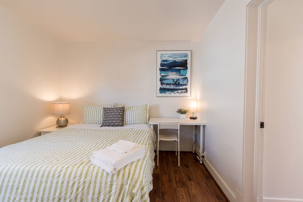 Wood-finish flooring throughout this room, featuring a built-in white desk with overhead art, and a white painted trim door frame