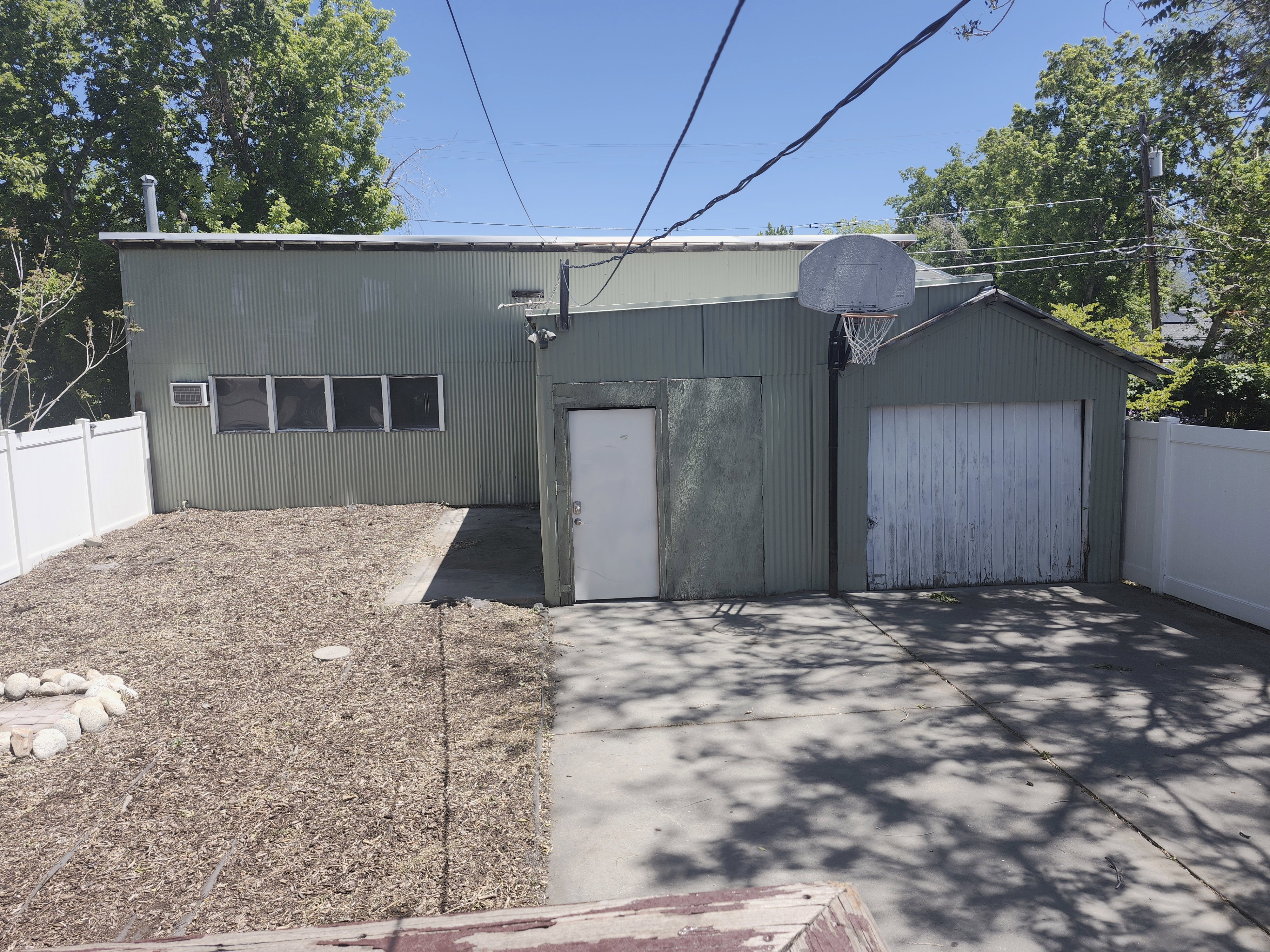 Detached corrugated metal structure featuring multiple windows, a garage door, and a separate entry door