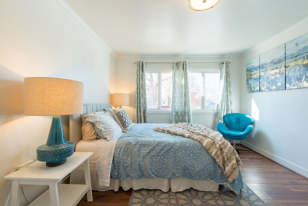 Bedroom featuring hardwood-style flooring, crown molding, and two windows with patterned drapes