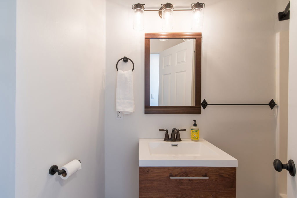 Bathroom vanity featuring a wood-finish cabinet, integrated white sink, and bronze-finish faucet