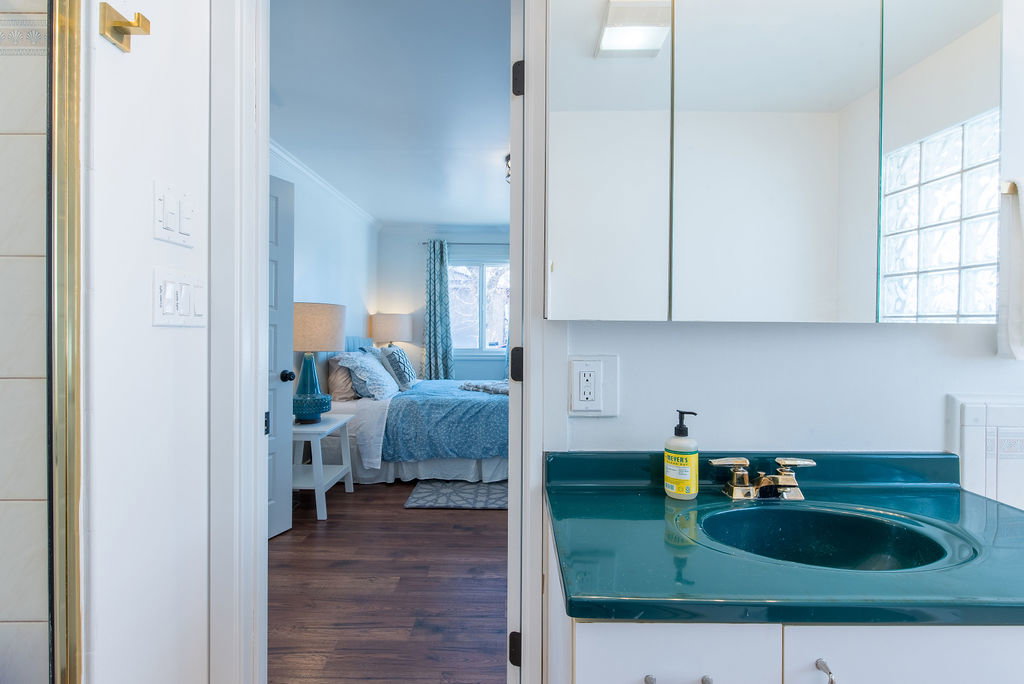 Bathroom vanity with integrated sink, brass-finish faucet, and overhead mirrored medicine cabinet