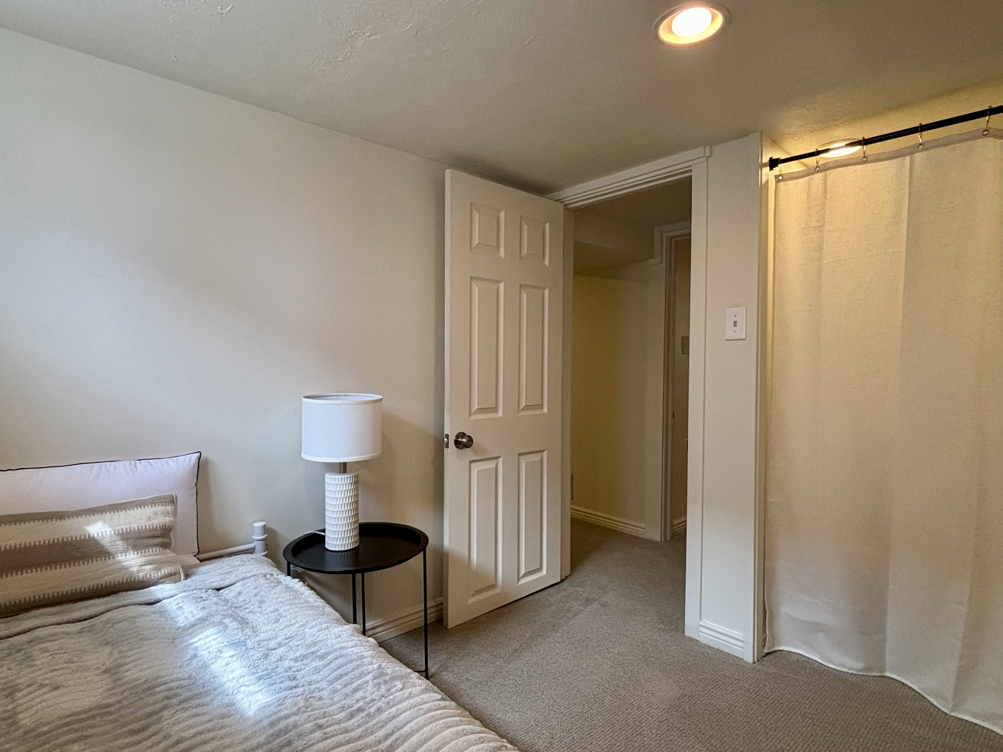 Carpeted room with recessed lighting, an interior door, and a curtained opening
