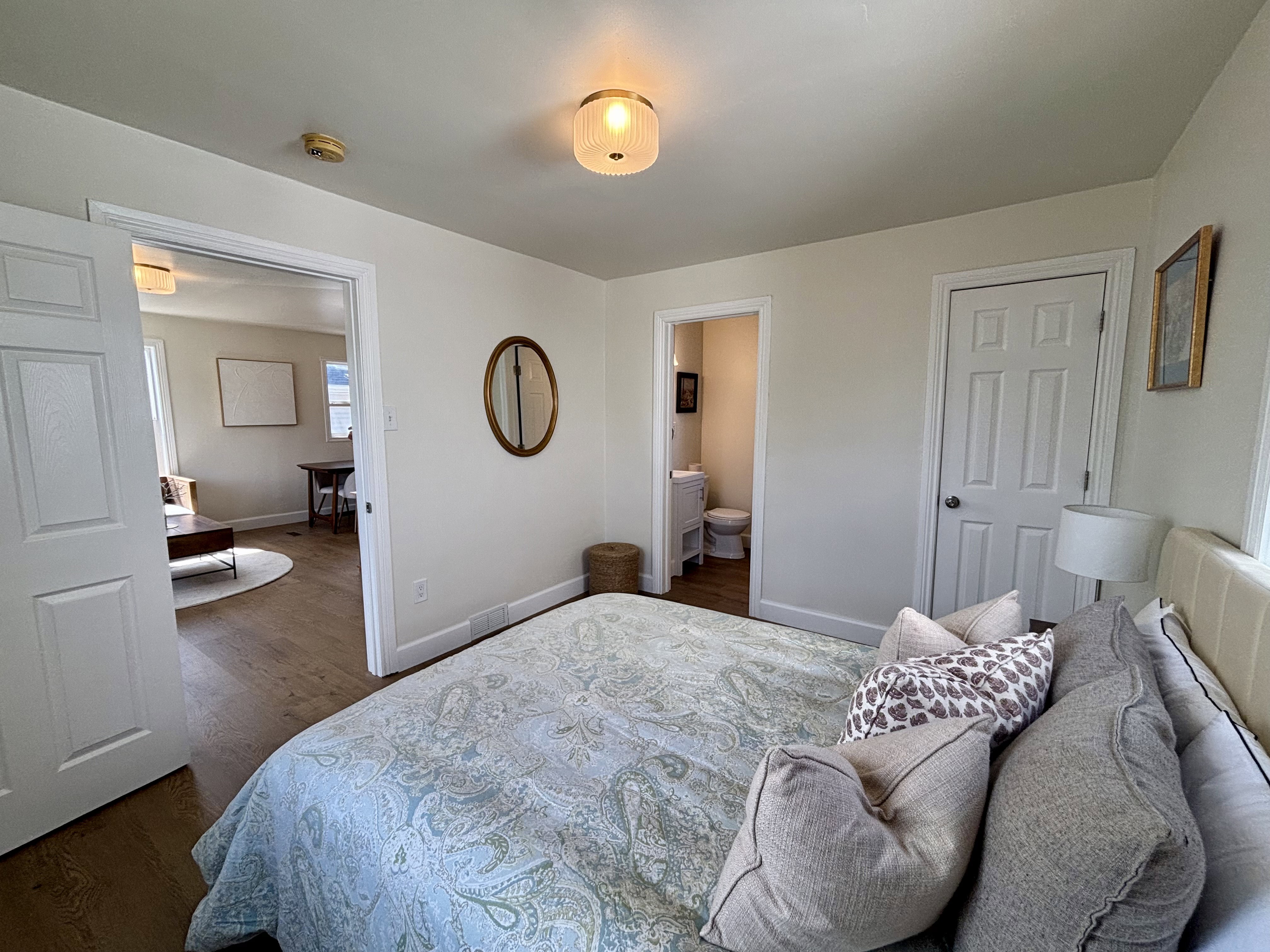 Interior room featuring neutral wall tones, wood-finish flooring, a paneled door, and an overhead light fixture