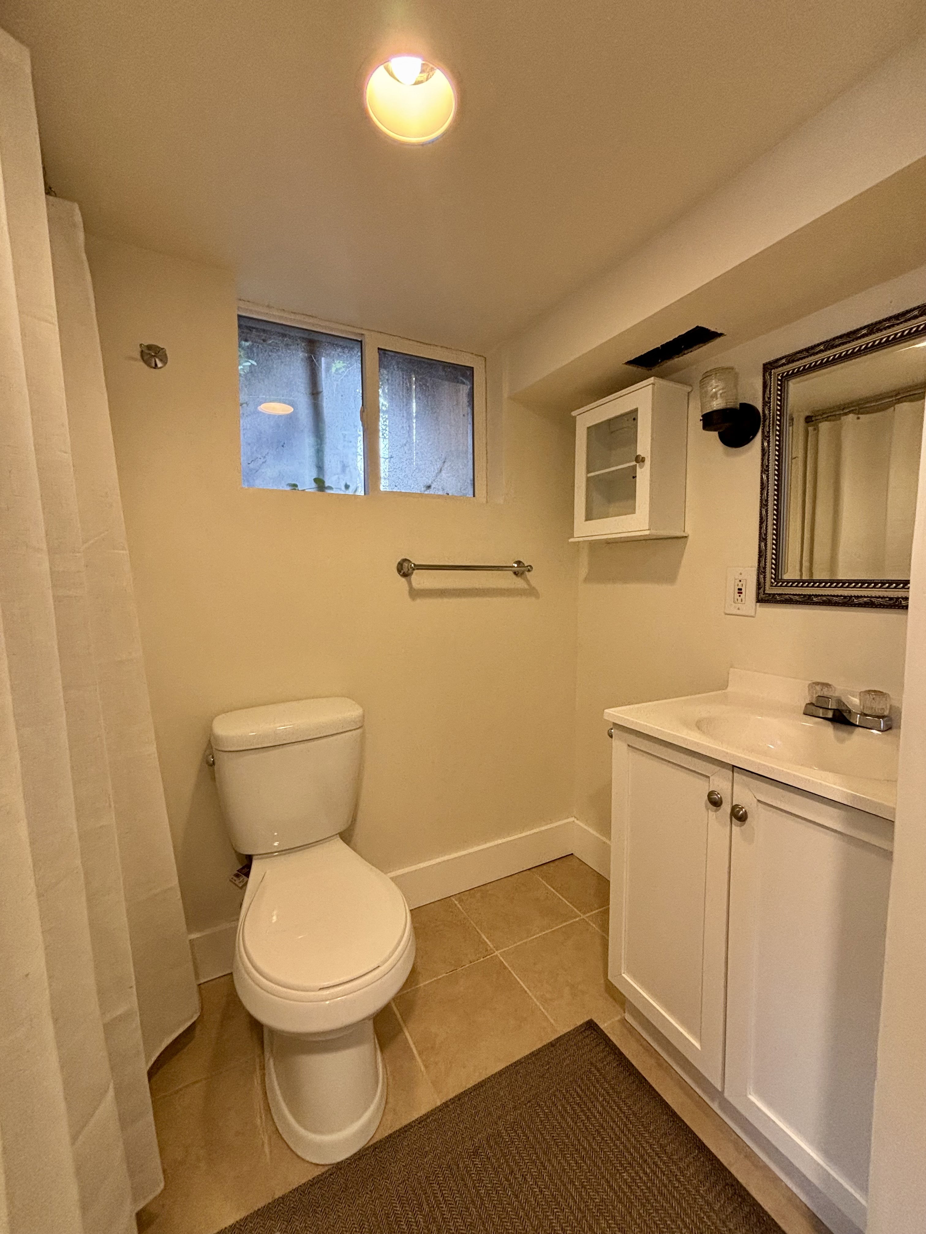 Bathroom featuring a white vanity with built-in sink, framed mirror, and tiled flooring